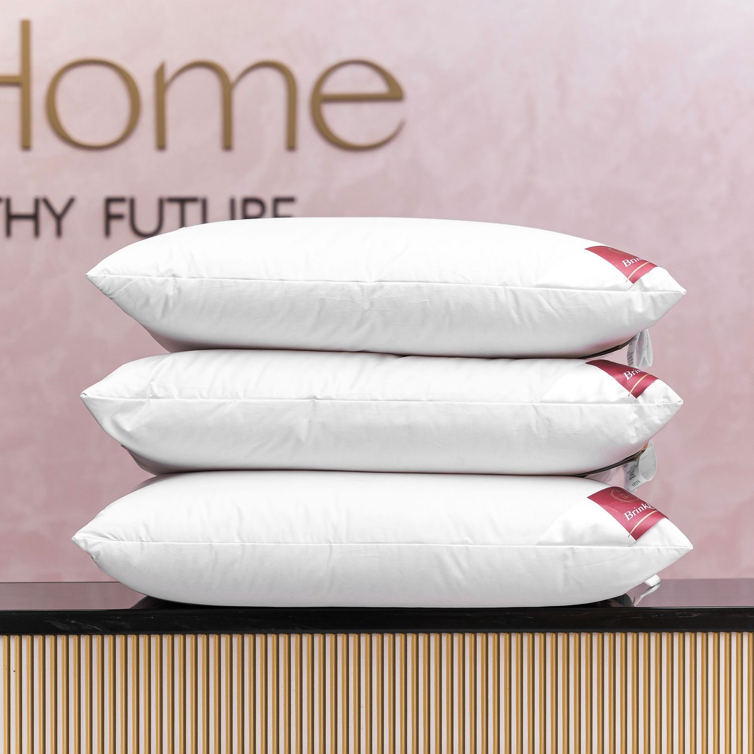 Stack of white luxury bed pillows with branded tags against pink background.