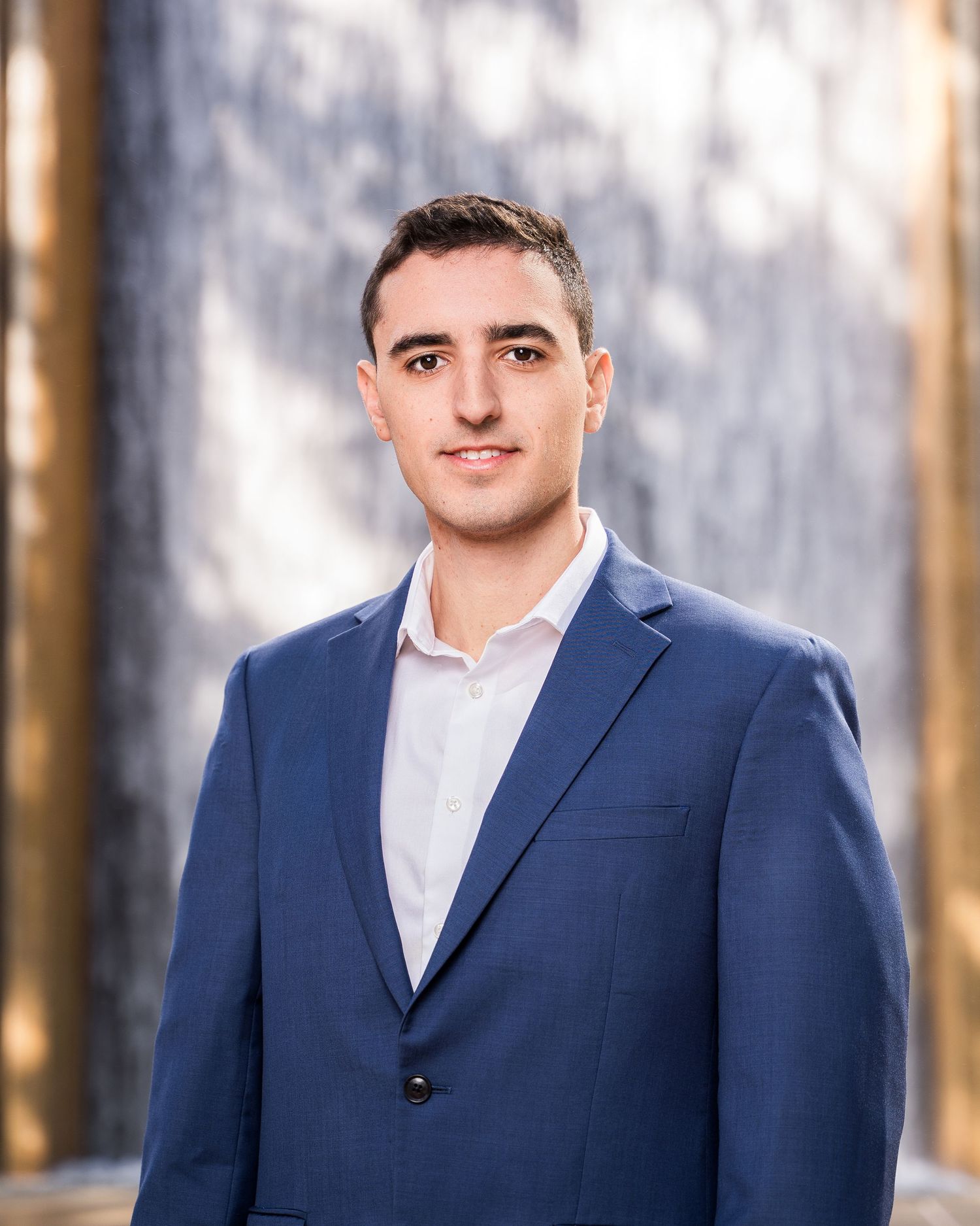 Professional headshot against textured background in navy suit.