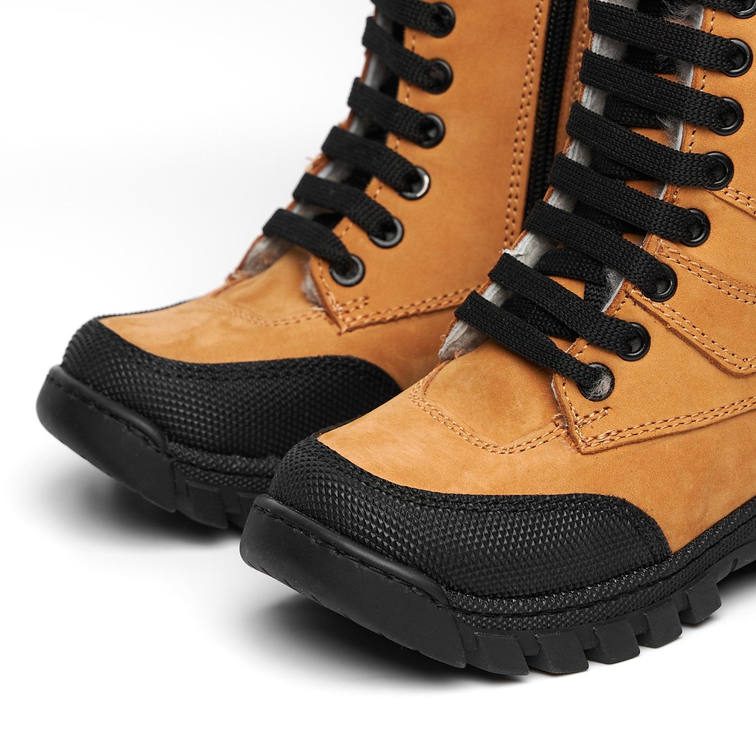 Close-up of tan leather combat boots with black rubber toe cap and laces.