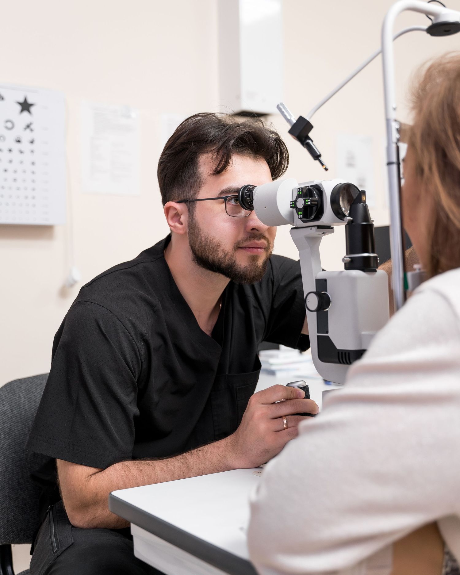 Eye doctor using slit lamp biomicroscope for patient examination.