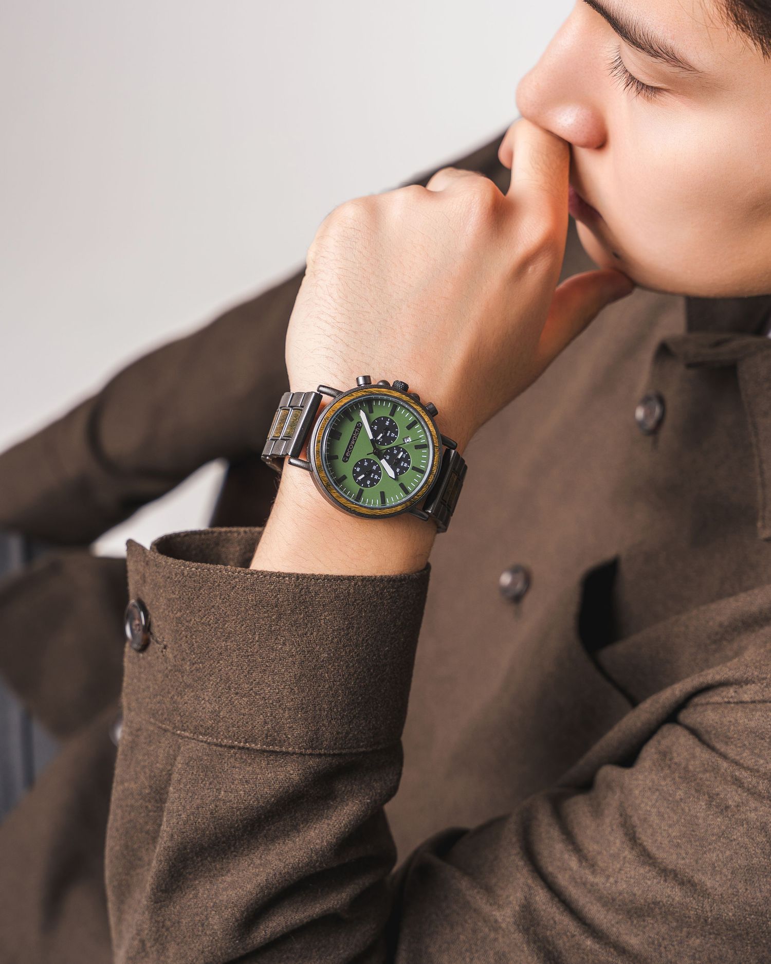 Close-up shots of wrist watch with green dial worn with brown sweater.