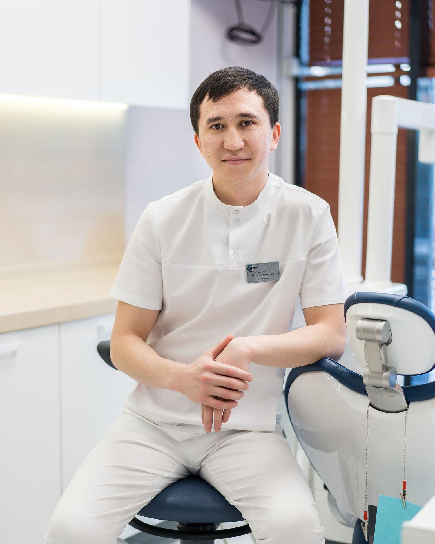 Medical professional in white uniform seated in modern clinical environment.