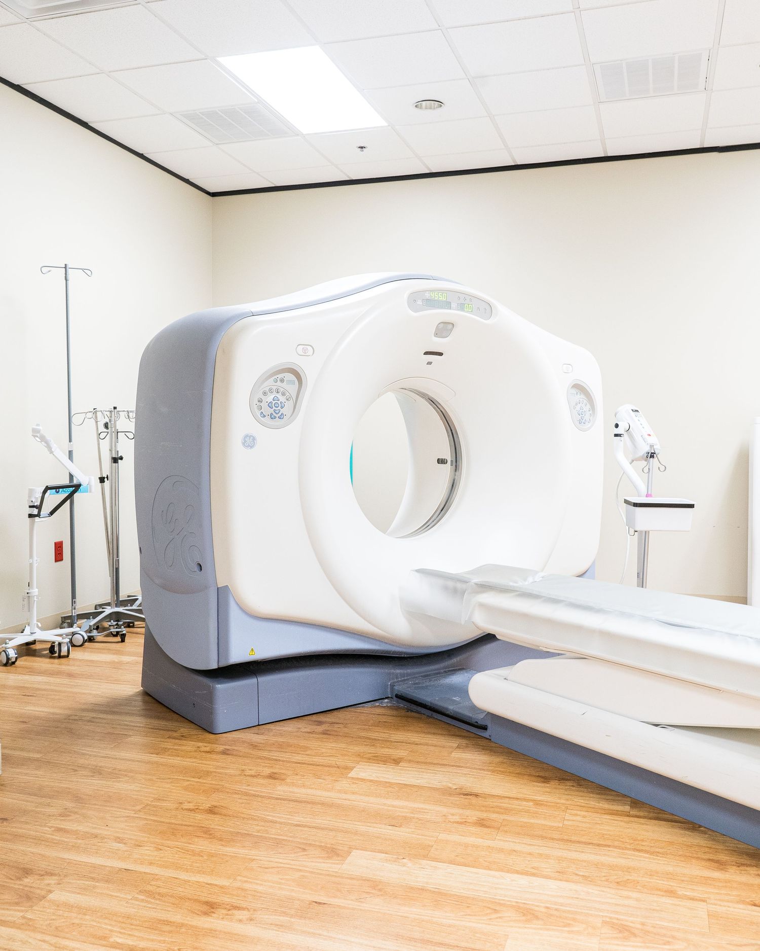 Medical imaging equipment and CT scanners line a modern healthcare facility with wooden floors.
