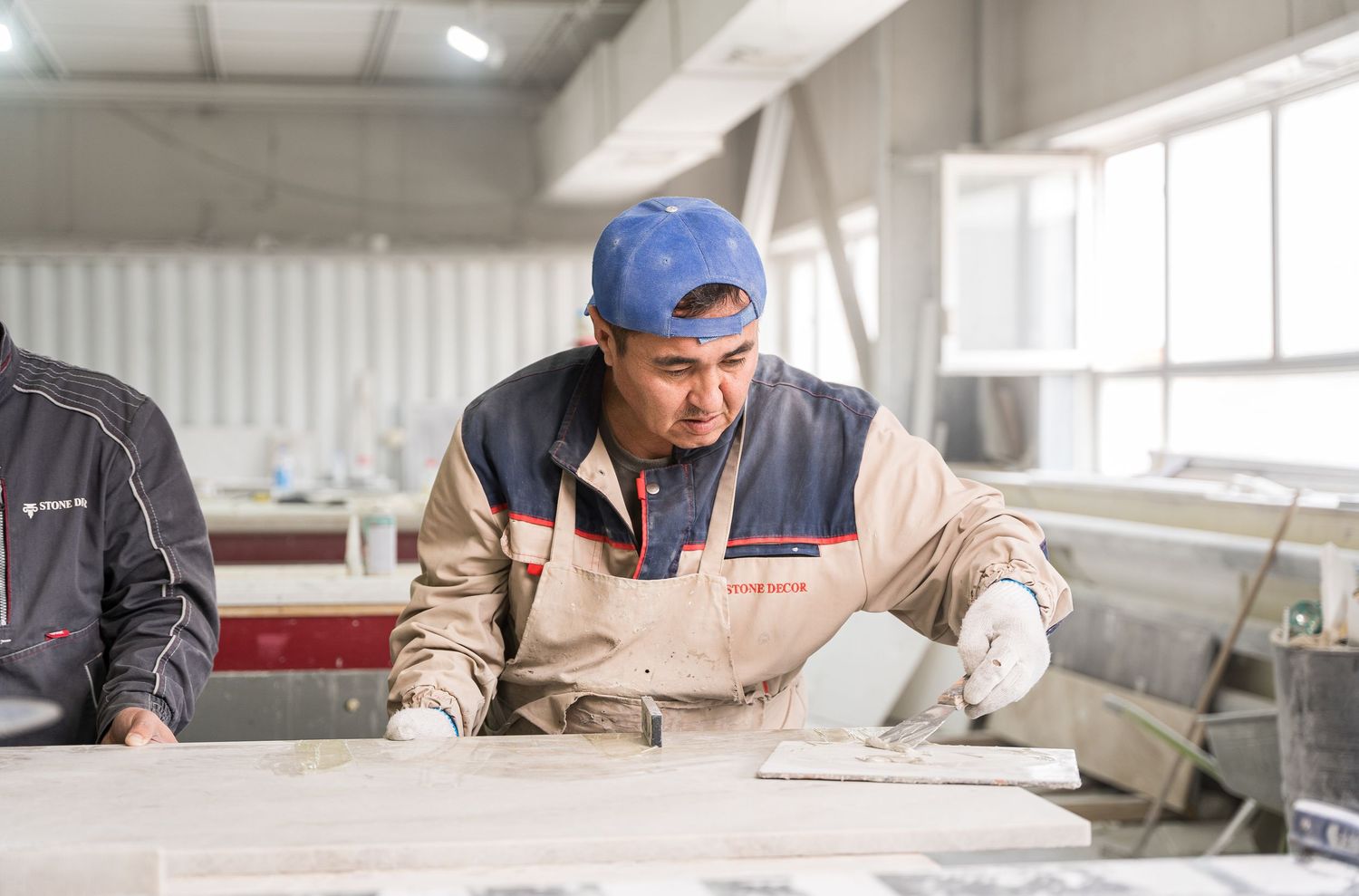 Workers examining and measuring stone materials in a bright industrial workspace.