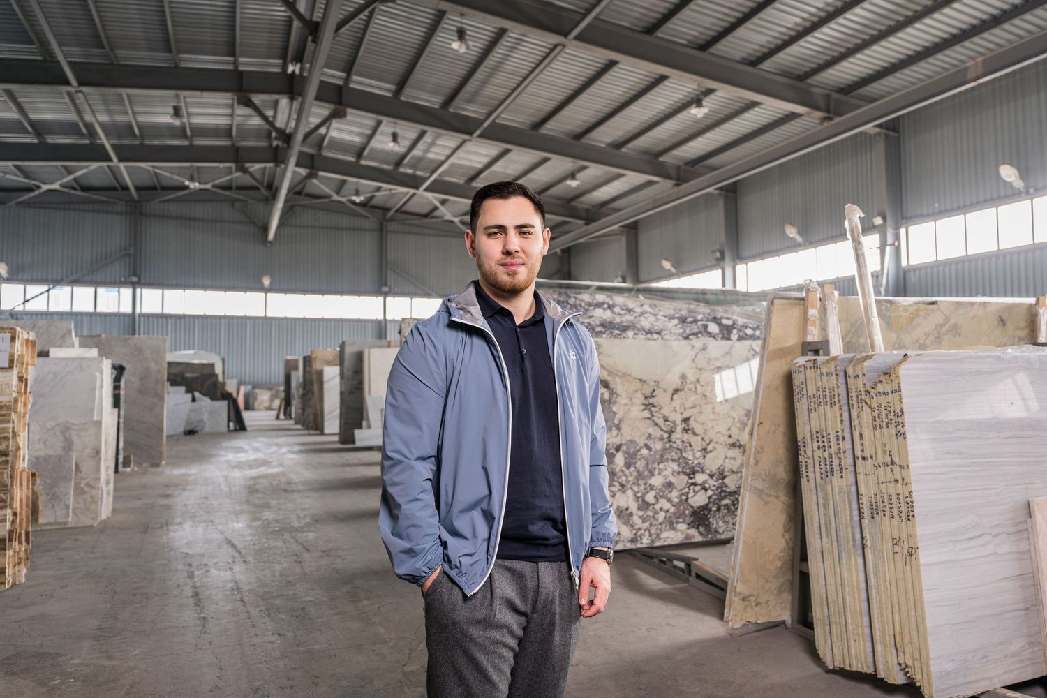 Professional in warehouse showroom with stone slabs and materials displayed in background.
