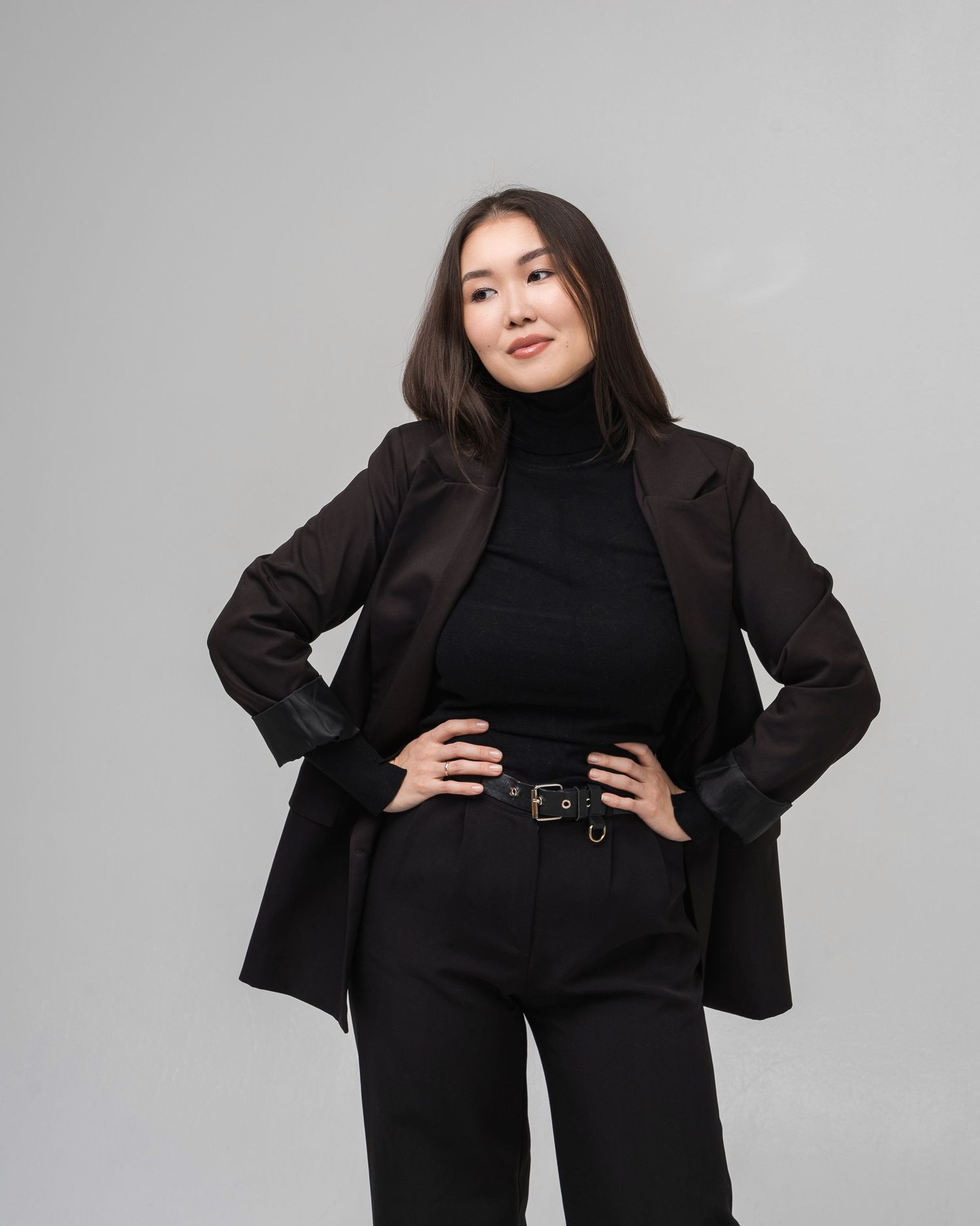 Fashion model showcases black business attire with dramatic poses on grey background.