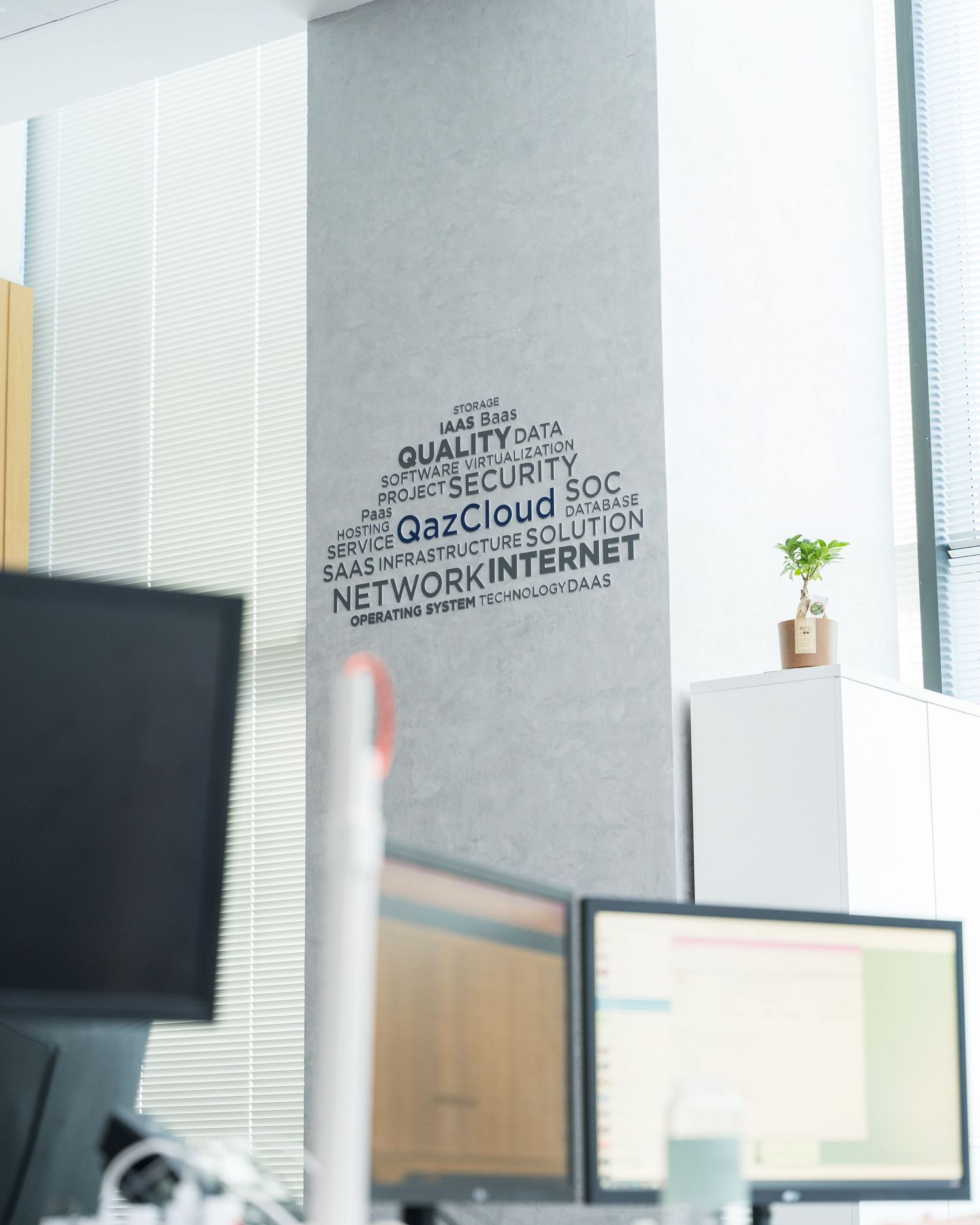 Word cloud wall art displaying tech-related terms like cloud and network in modern office space.