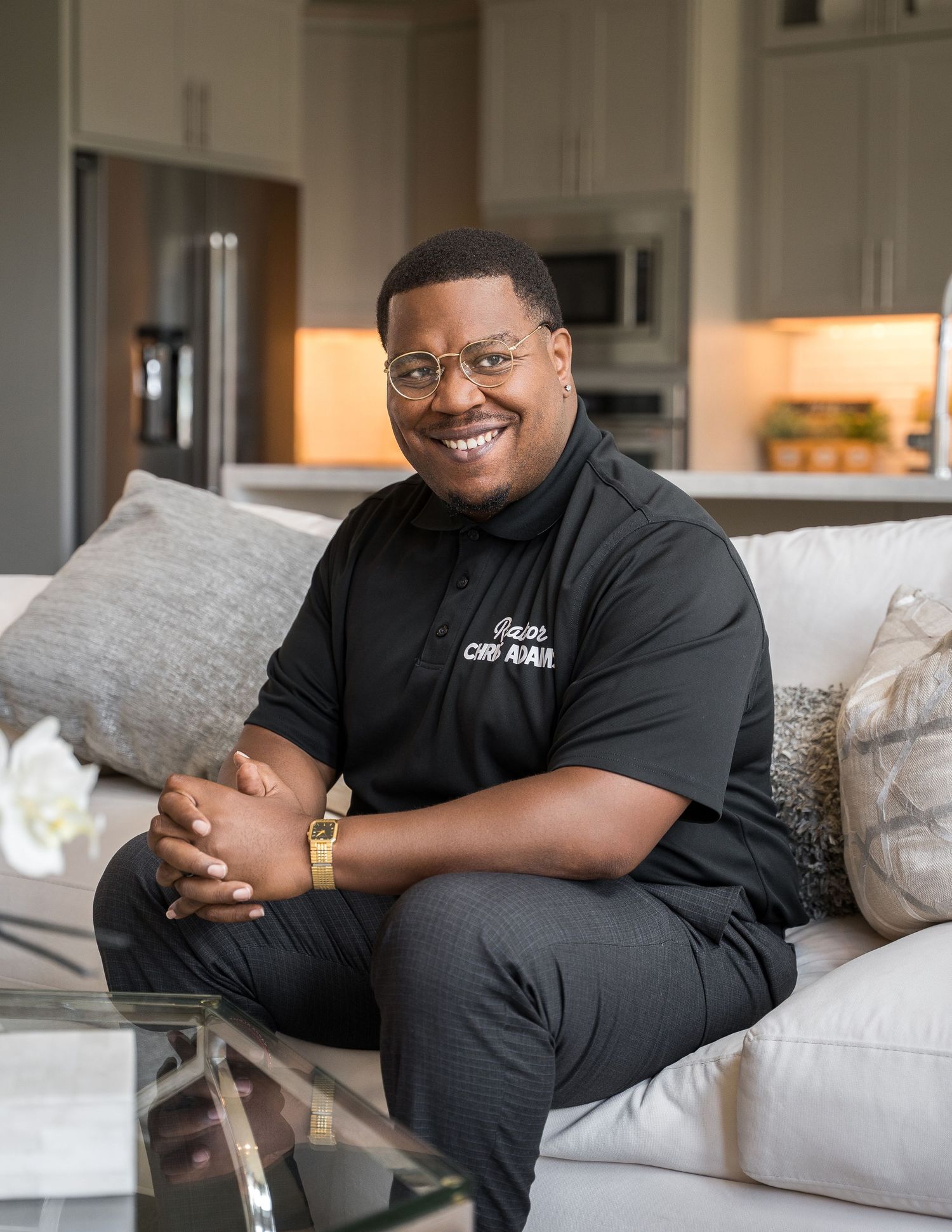 Individual relaxing on gray couch wearing casual black attire in modern living space.