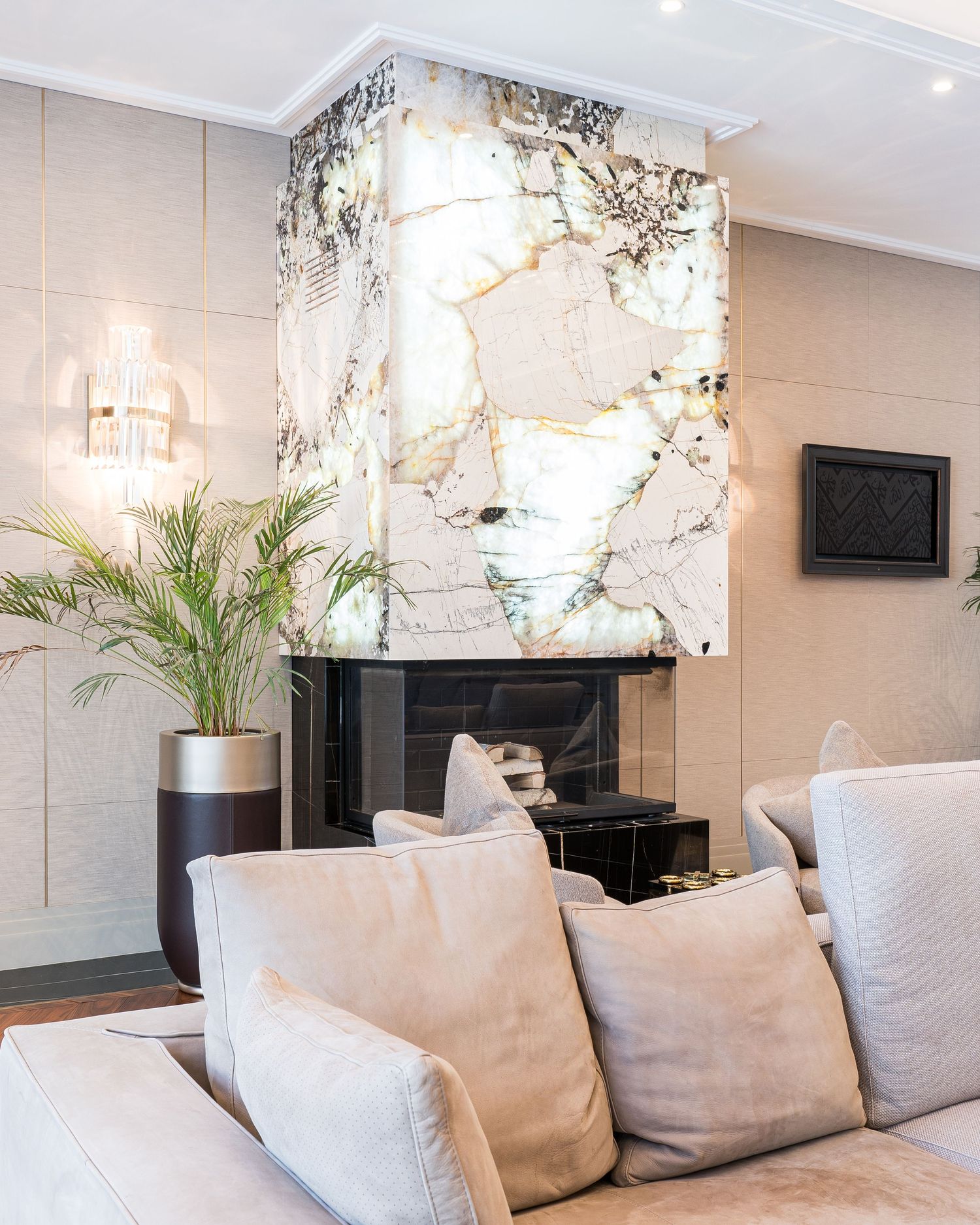 Elegant living space featuring light gray sofa, white marble walls, and contemporary chandelier.