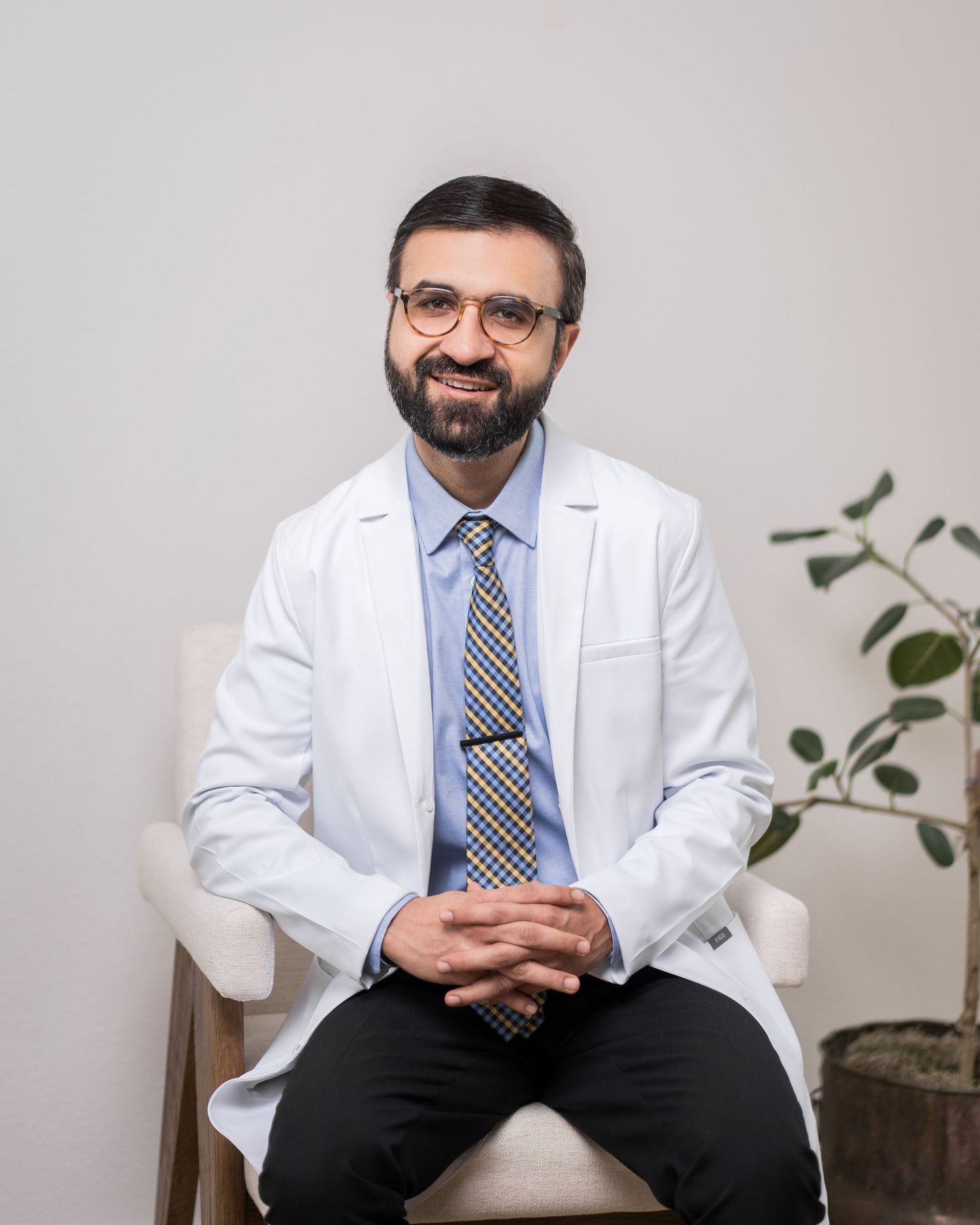 Healthcare provider in white coat sitting at consultation desk.