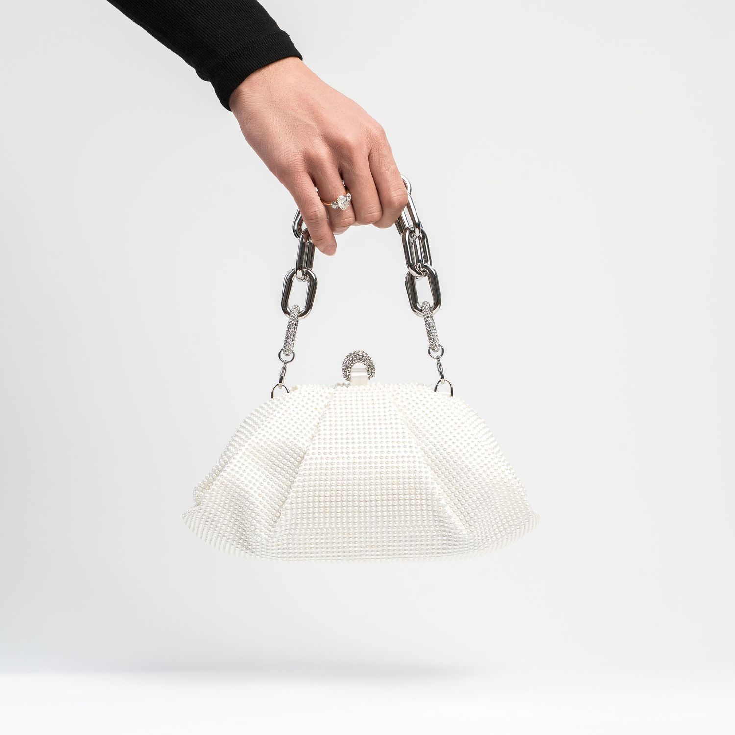White textured handbag with silver chain handles shown floating against white background.