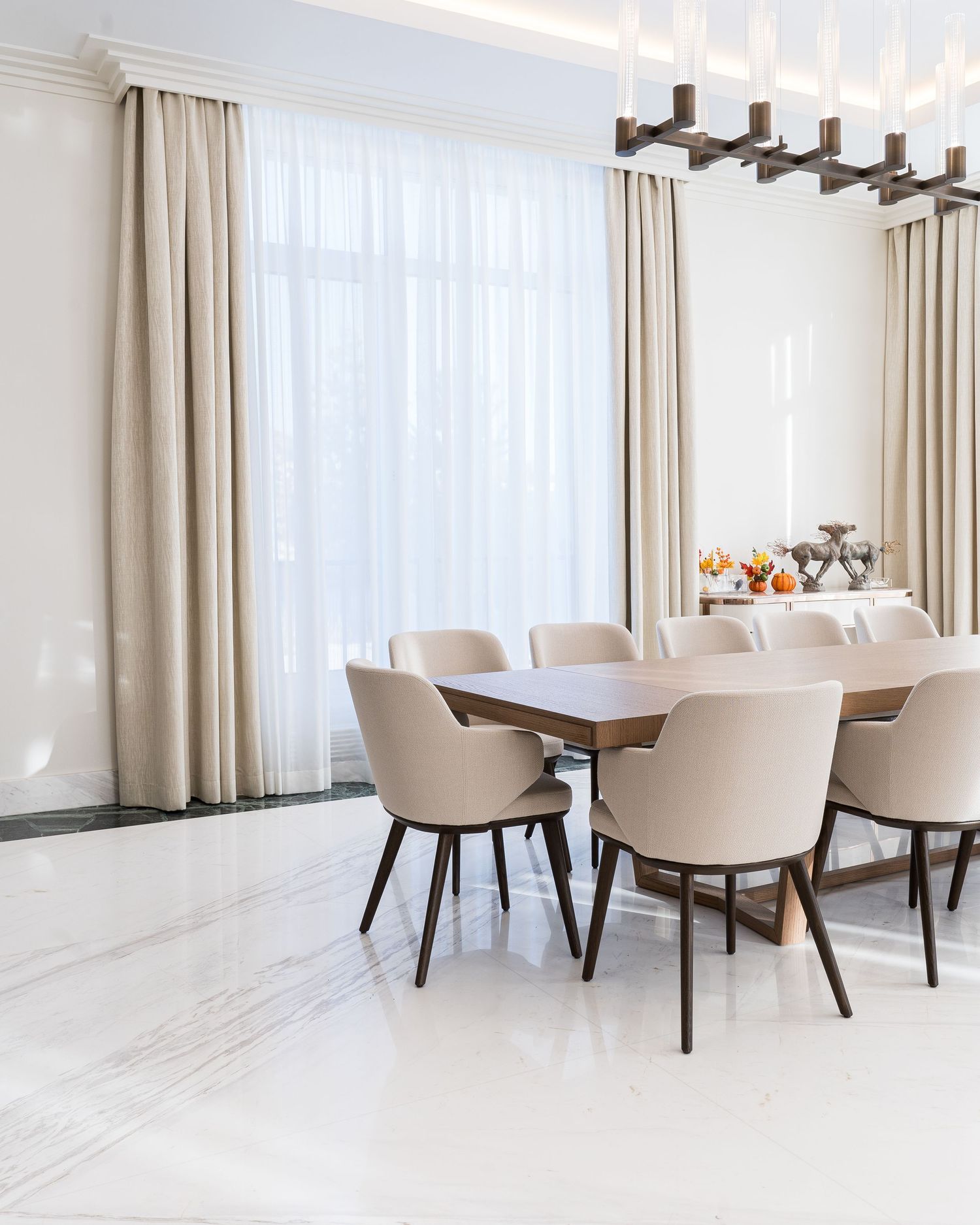Elegant dining room with cream upholstered chairs and modern chandelier lighting.