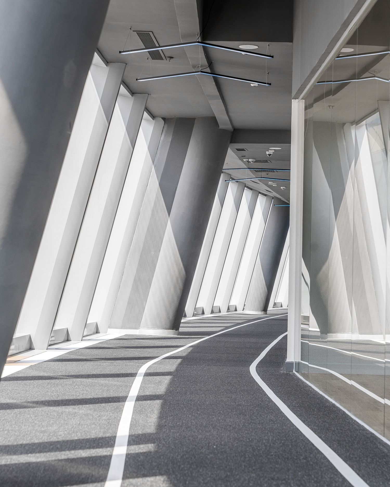 Futuristic white corridor with angular walls and geometric lighting design creating dramatic shadows.