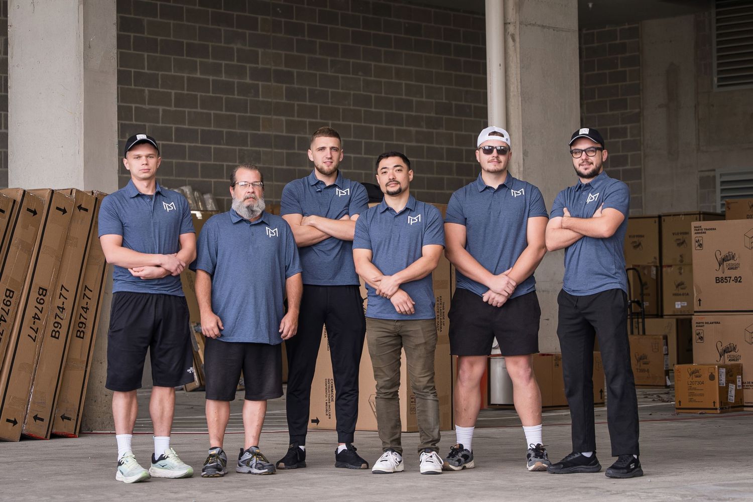 Group of maintenance staff in matching blue uniforms sitting on steps outside a building.