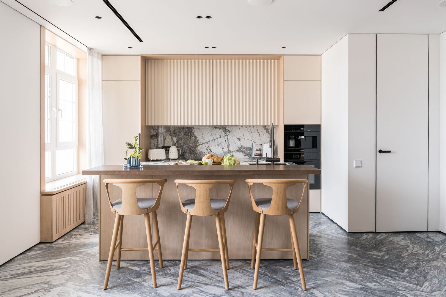 Contemporary open concept kitchen and dining space with light wood furniture and clean white walls.