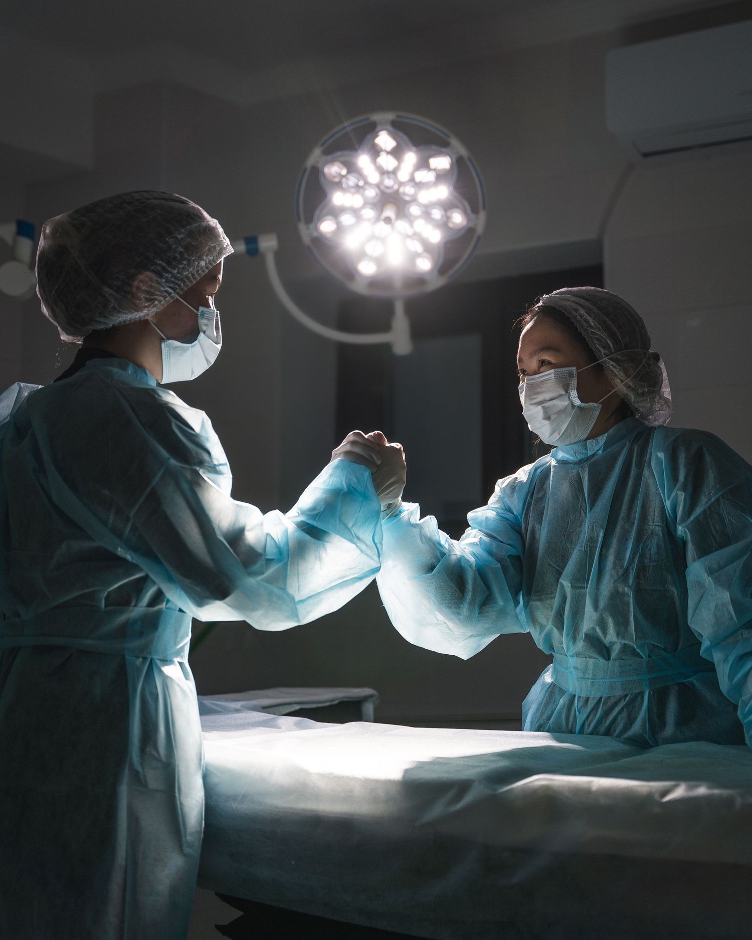 Surgical team performing operation under bright medical lights in hospital operating room.