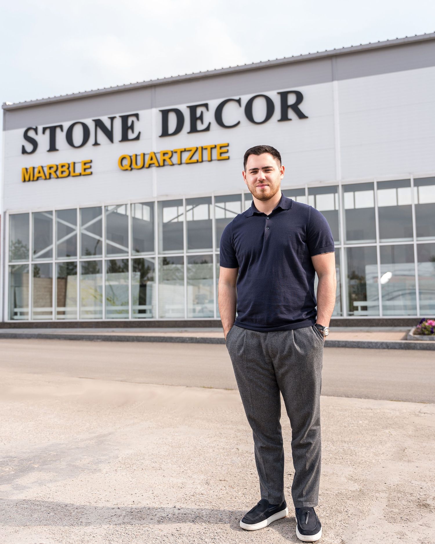 Professional standing in front of Stone Decor marble and quartzite storefront wearing casual business attire.