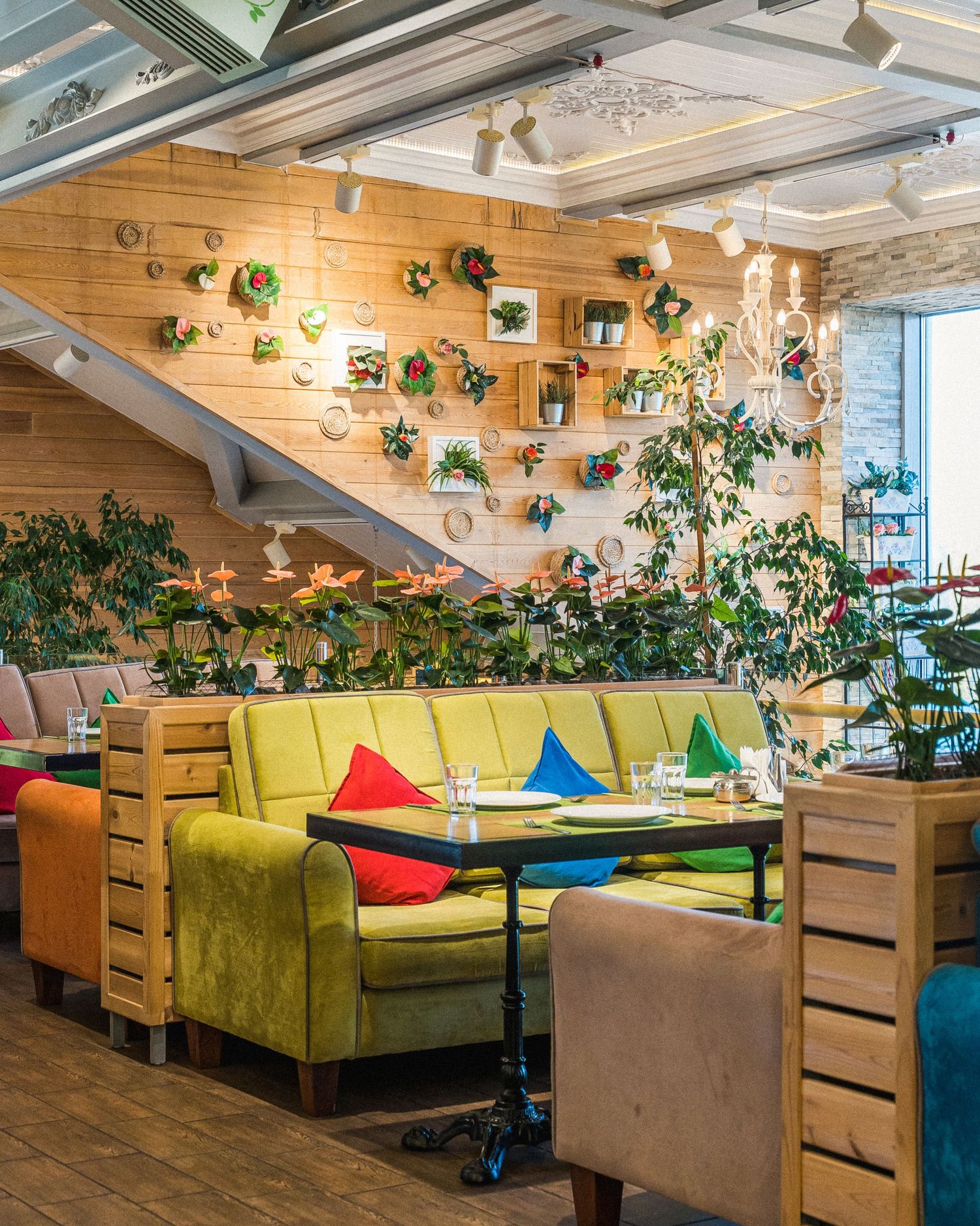 Restaurant seating area with colorful velvet couches and hanging plants creating a vibrant atmosphere.