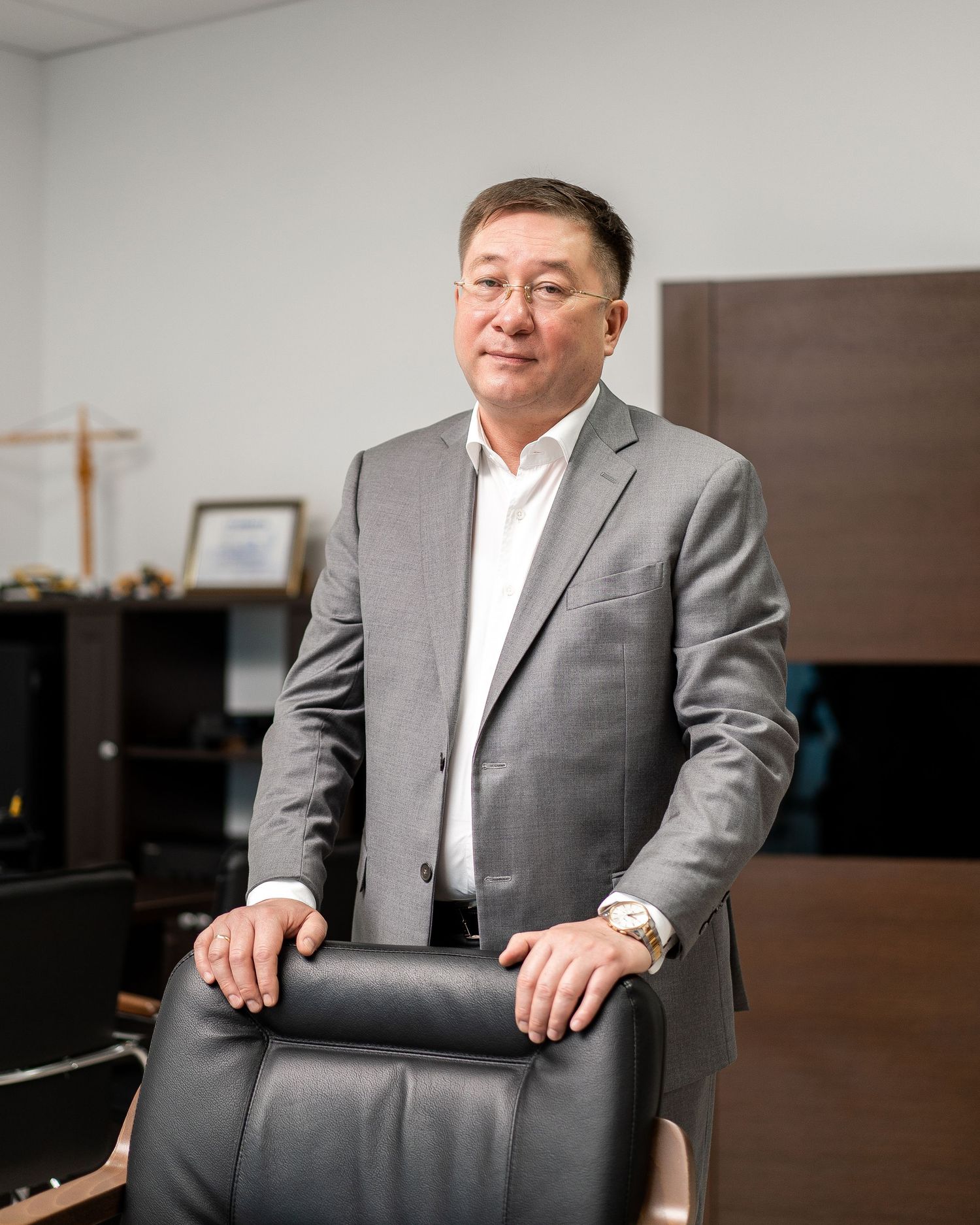Executive portrait session in gray suit seated in modern office environment.