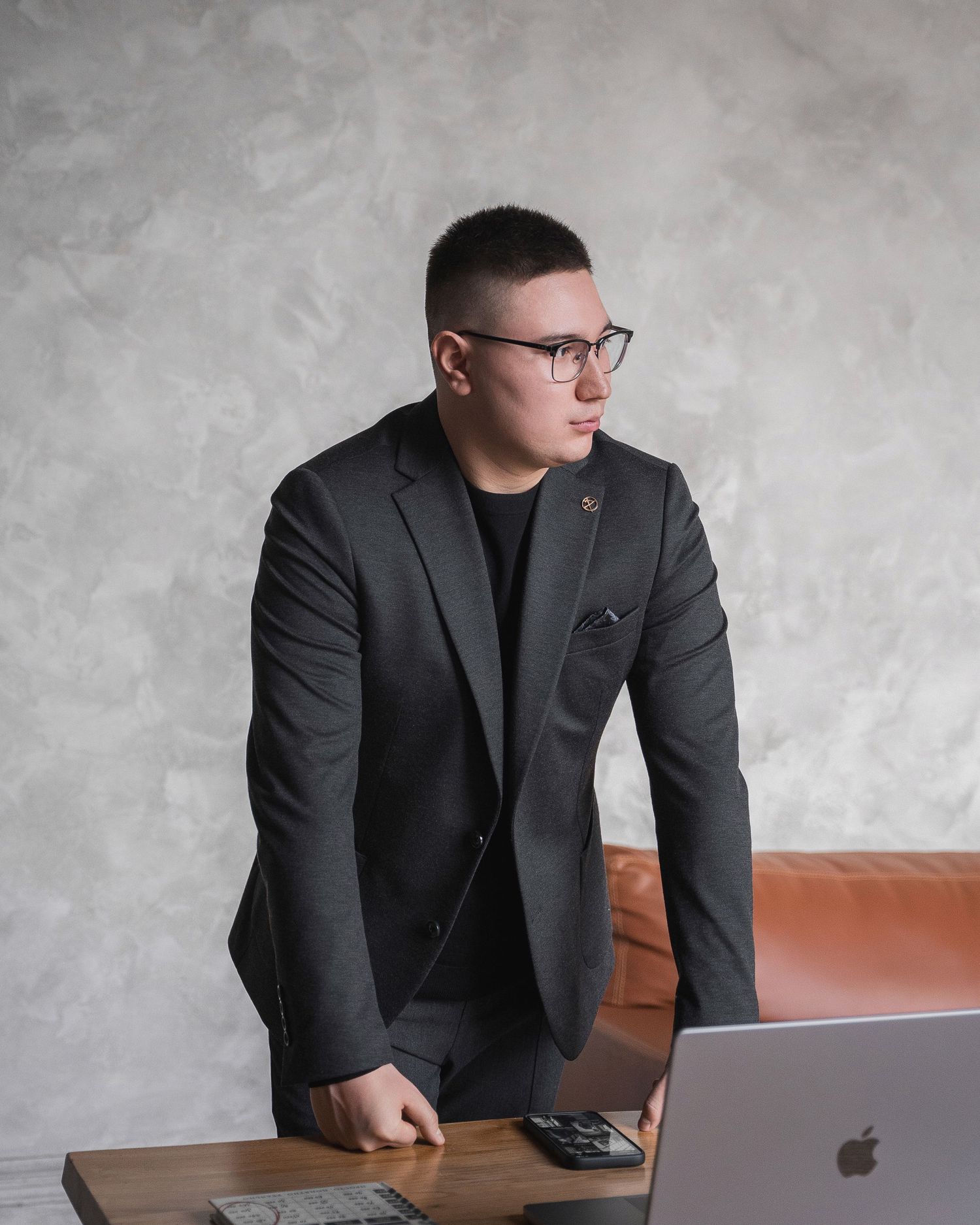 Business professional working at desk with MacBook and modern office setup.