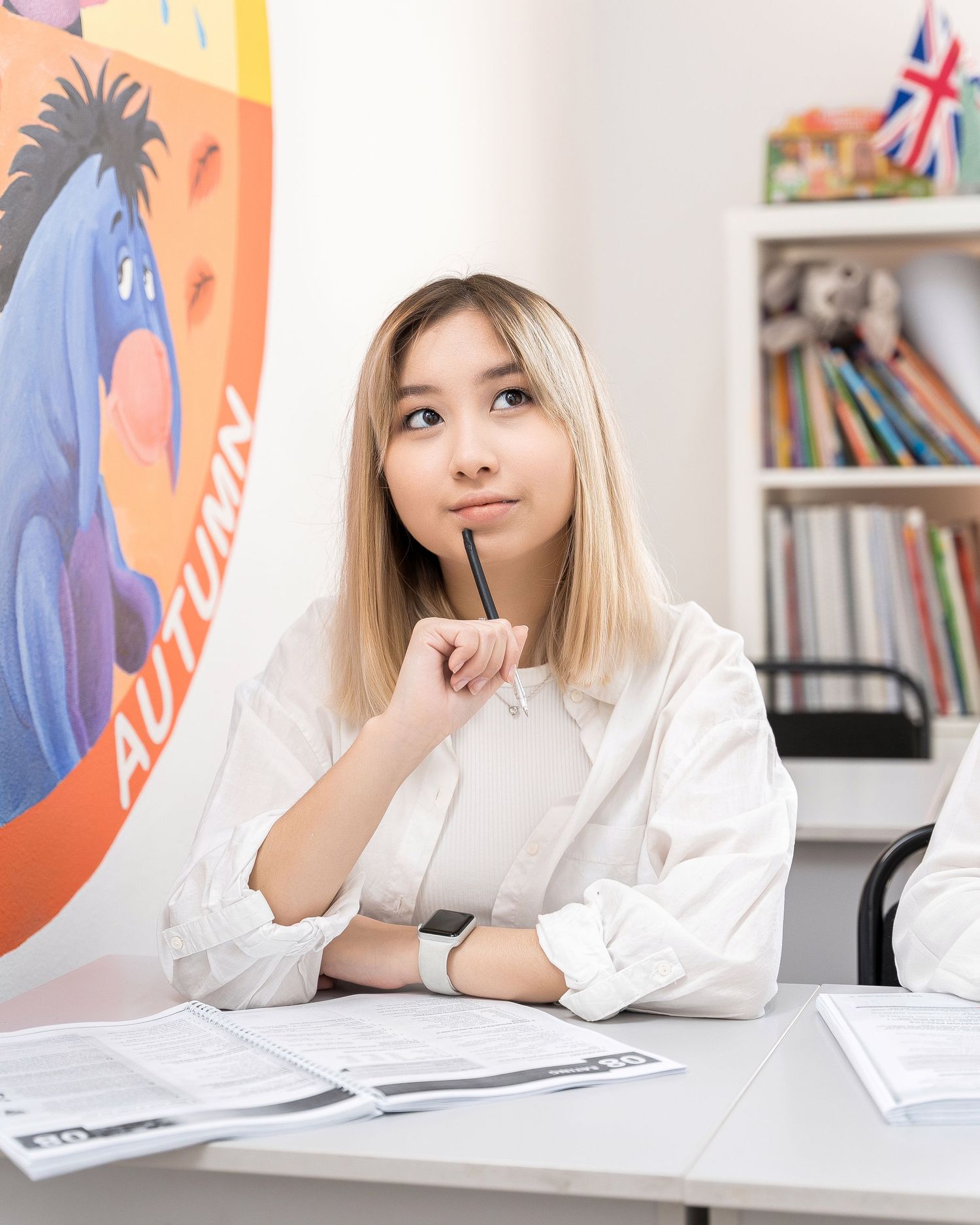 Student sitting at desk contemplating while studying in bright classroom environment.