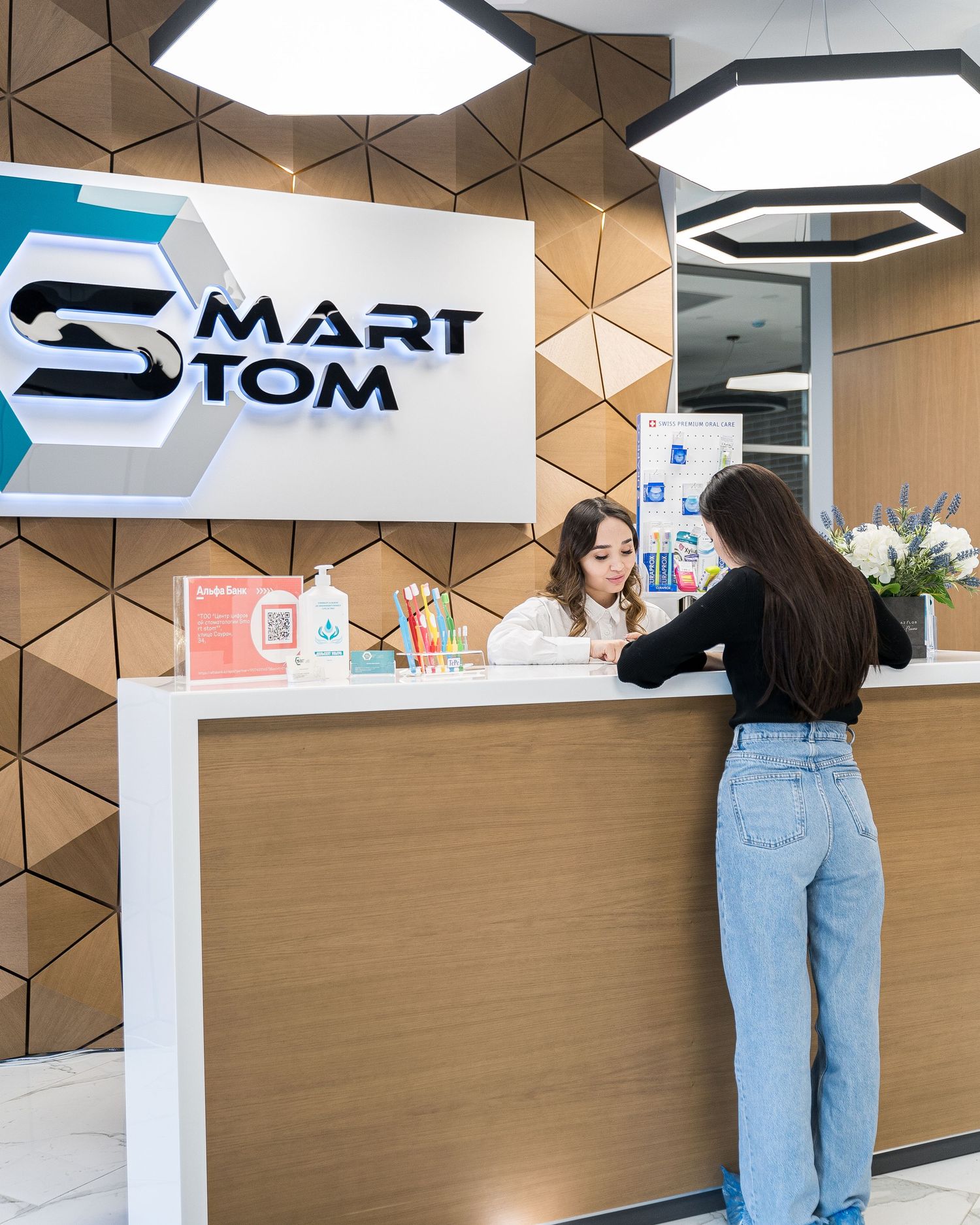 Modern clinic reception desk with geometric wall design and branded signage.