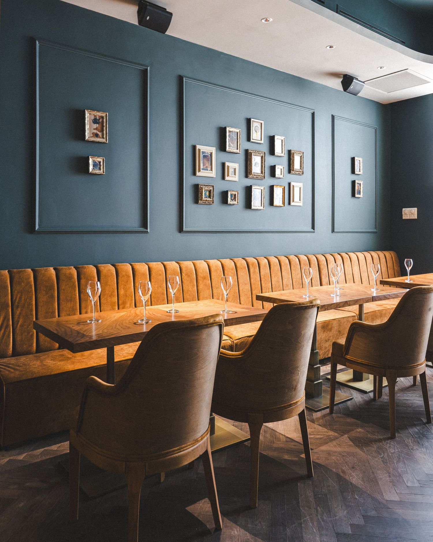 Moody restaurant lounge with deep teal walls and cognac leather banquette seating.