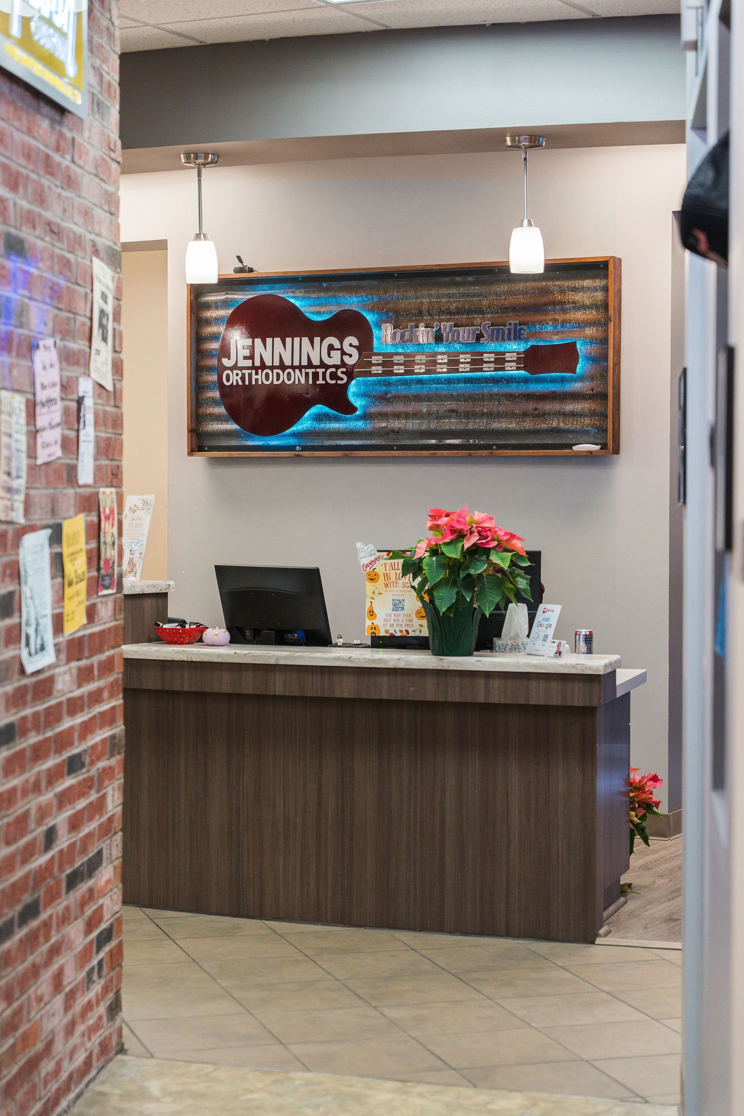 Modern dental office reception area with brick walls and illuminated signage.