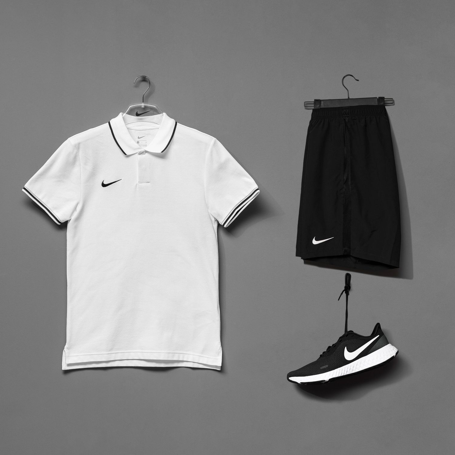 Nike sportswear set featuring white polo shirt and black shorts with matching shoes.