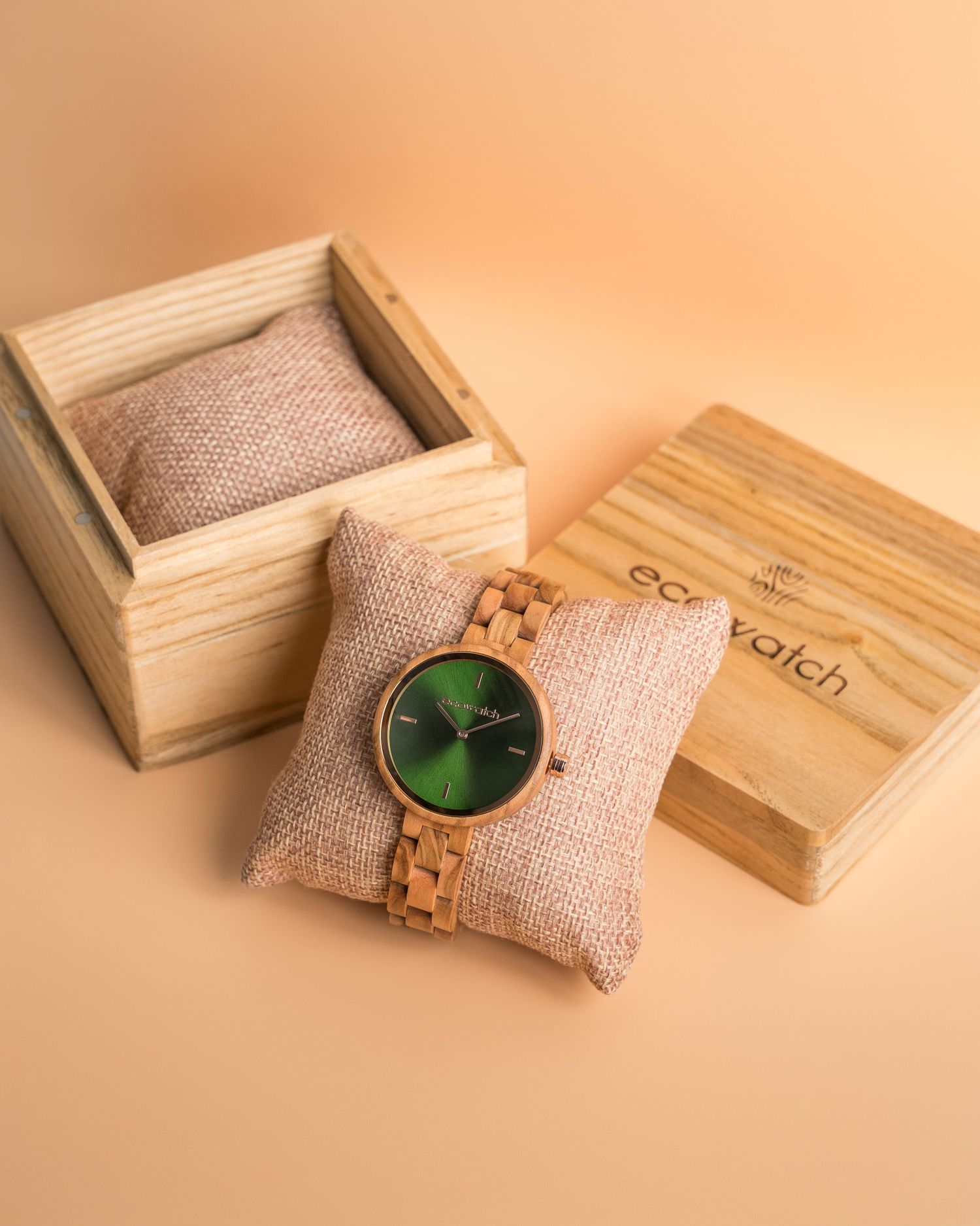 Eco-friendly wooden wristwatch with green dial presented on beige cushion in wooden box.