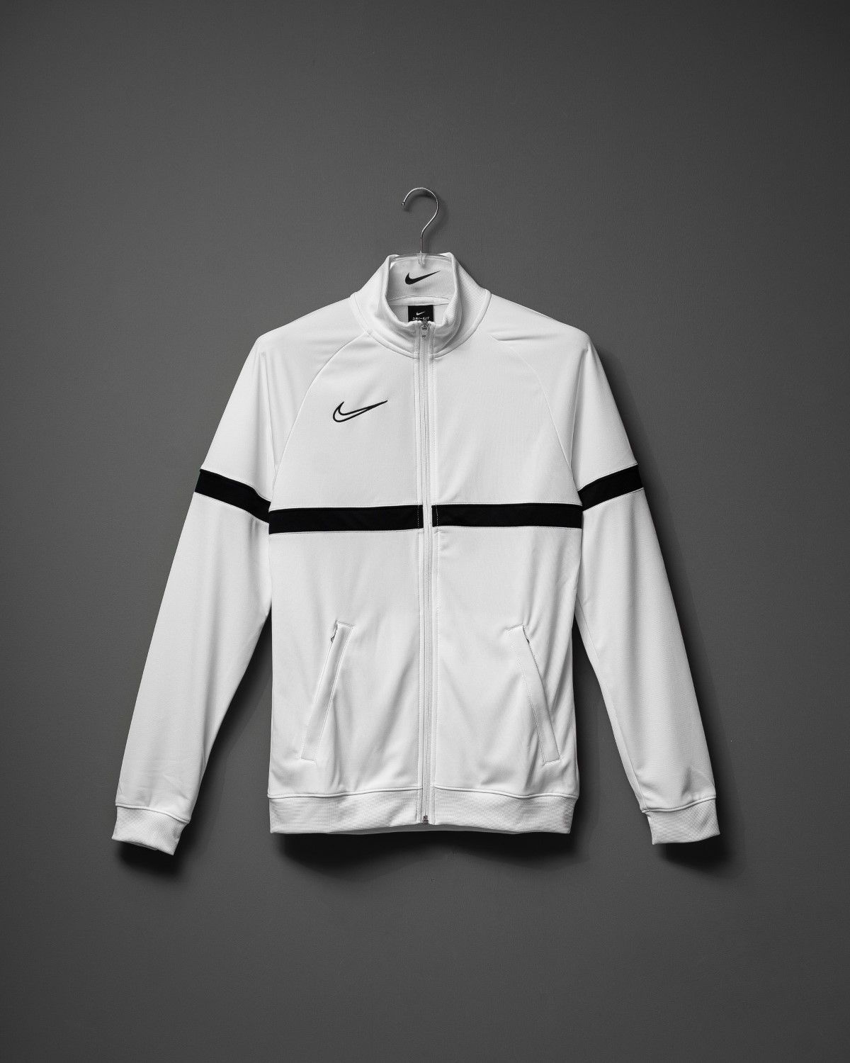 White Nike crop jackets arranged in a clean, minimal layout on grey background.