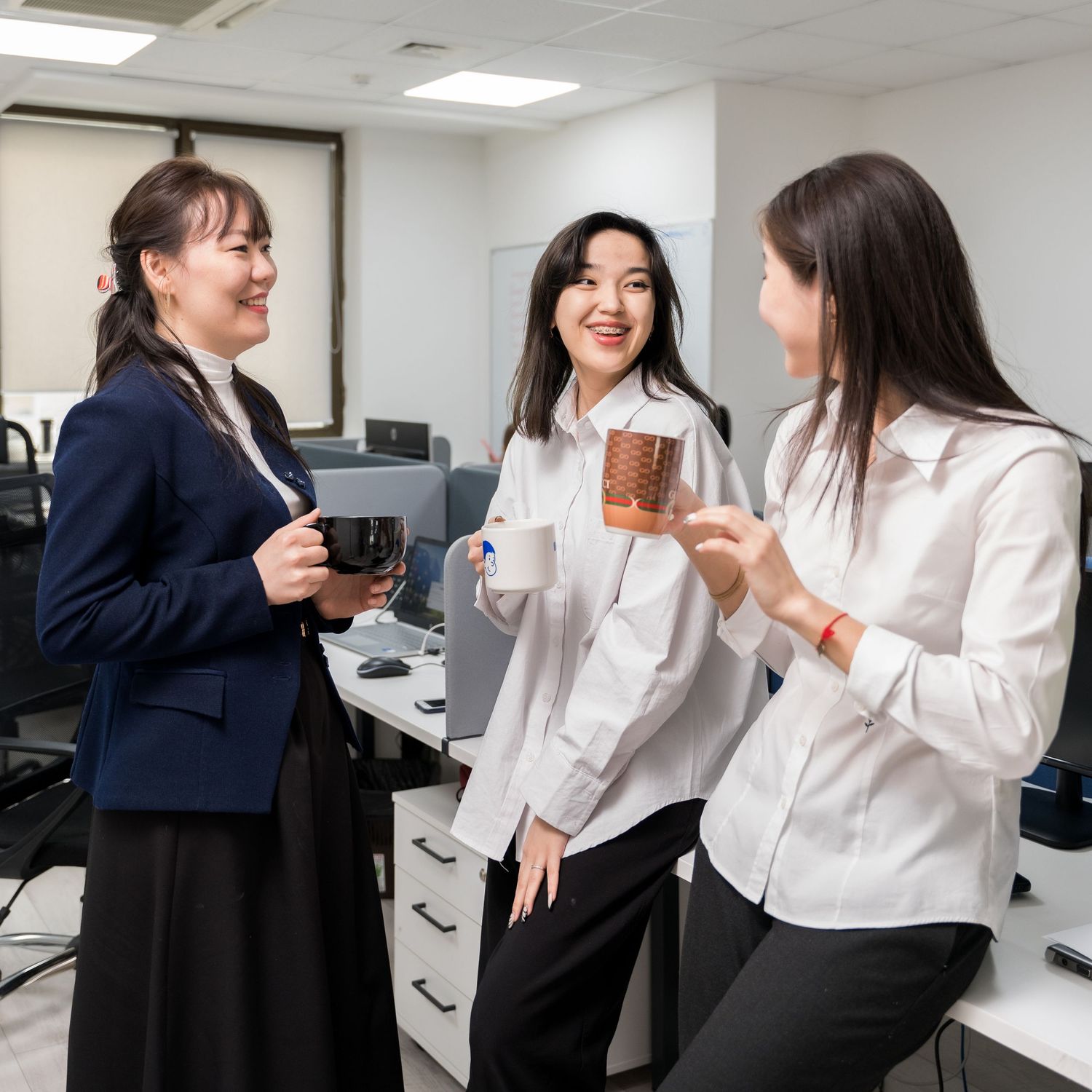 Office workers having casual conversation in bright workplace setting.