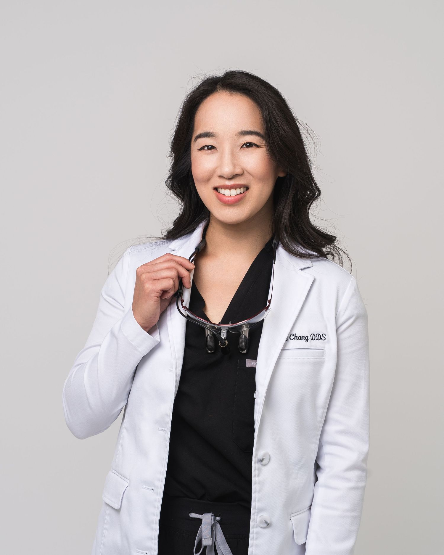 Healthcare professional in white coat against grey background.