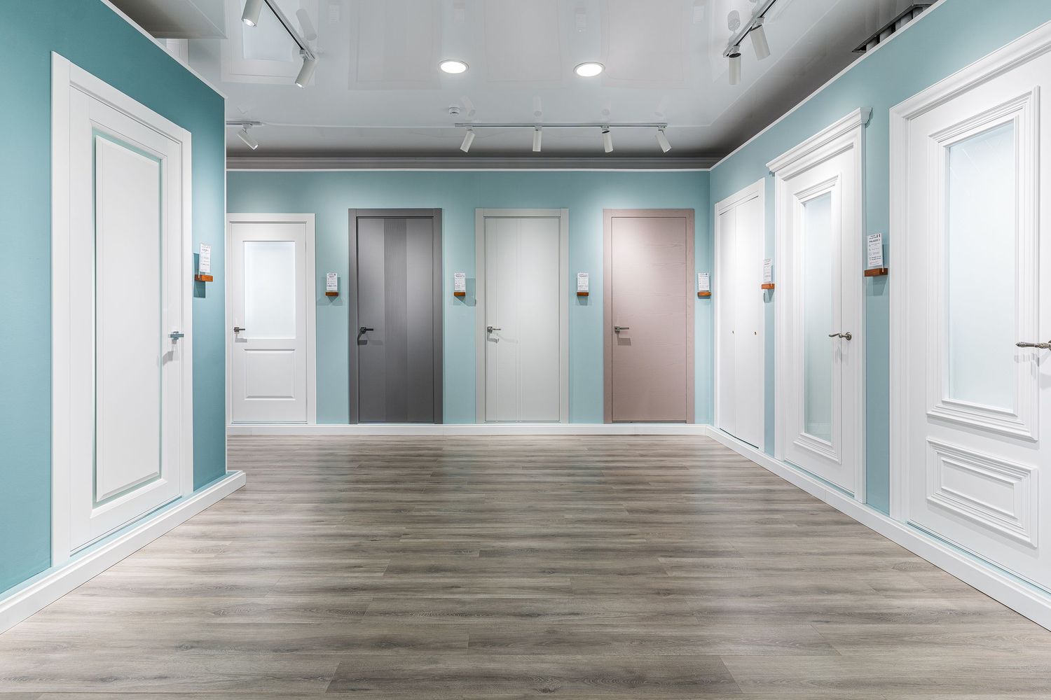 Empty office hallway with seafoam green walls and light wood floors.