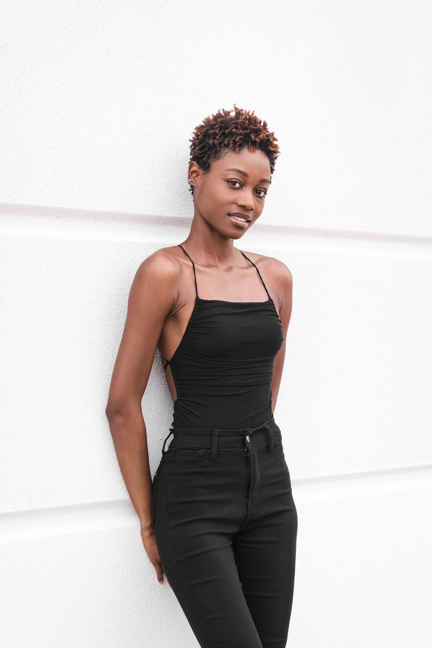 Series of fashion poses against white wall in all-black outfit.