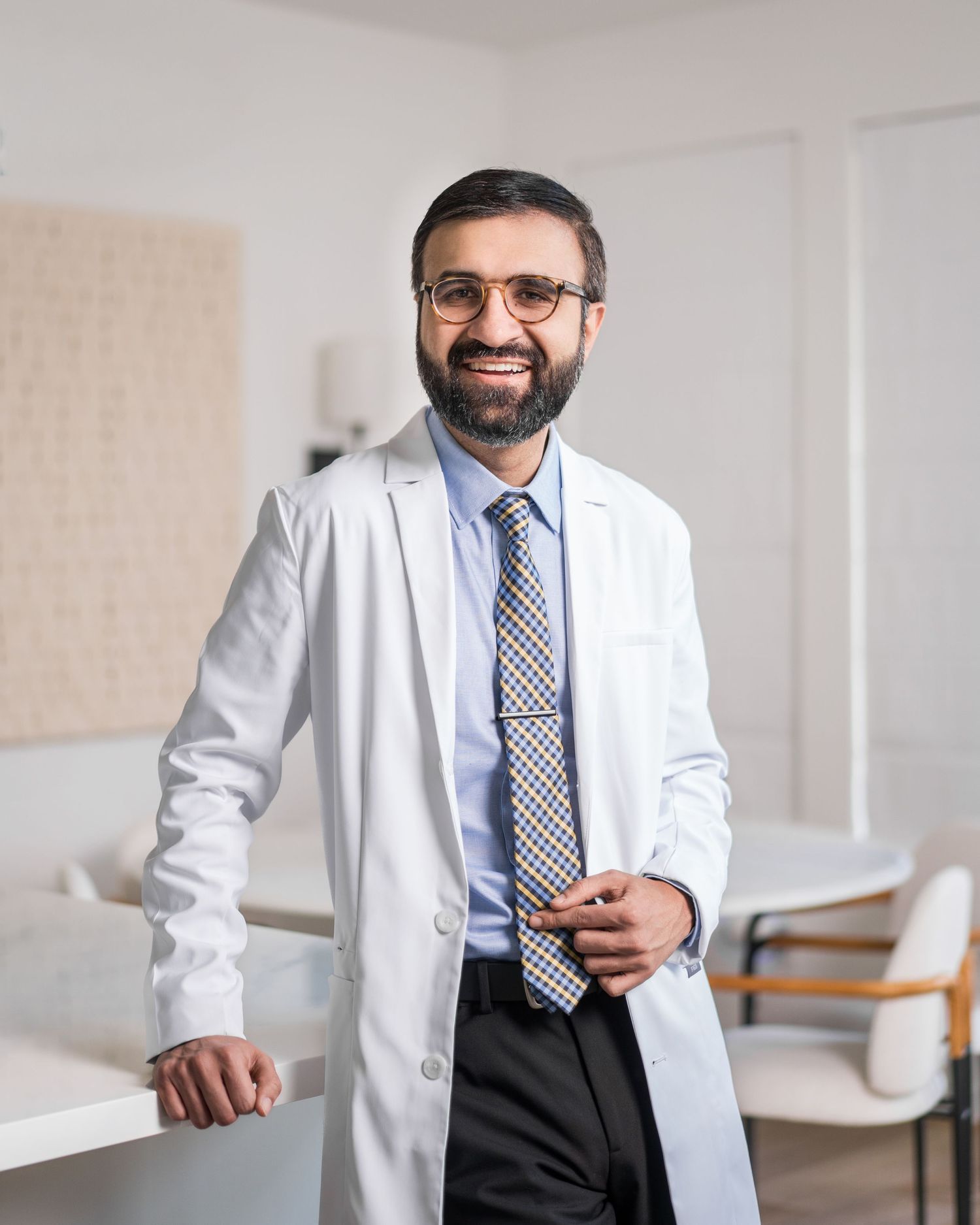 Healthcare provider in white coat and tie posing in medical office.