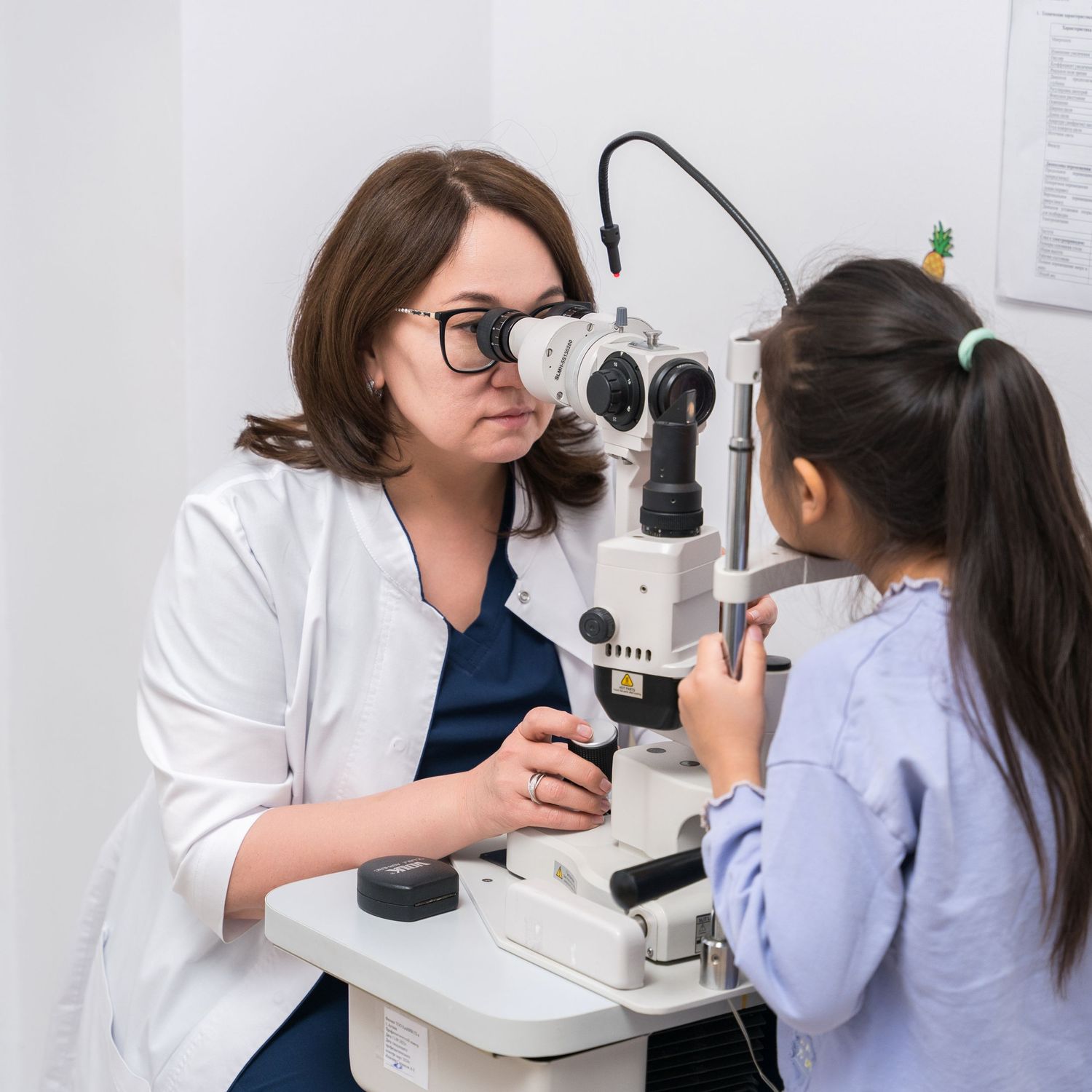 Medical professional using specialized eye examination equipment with a young patient.