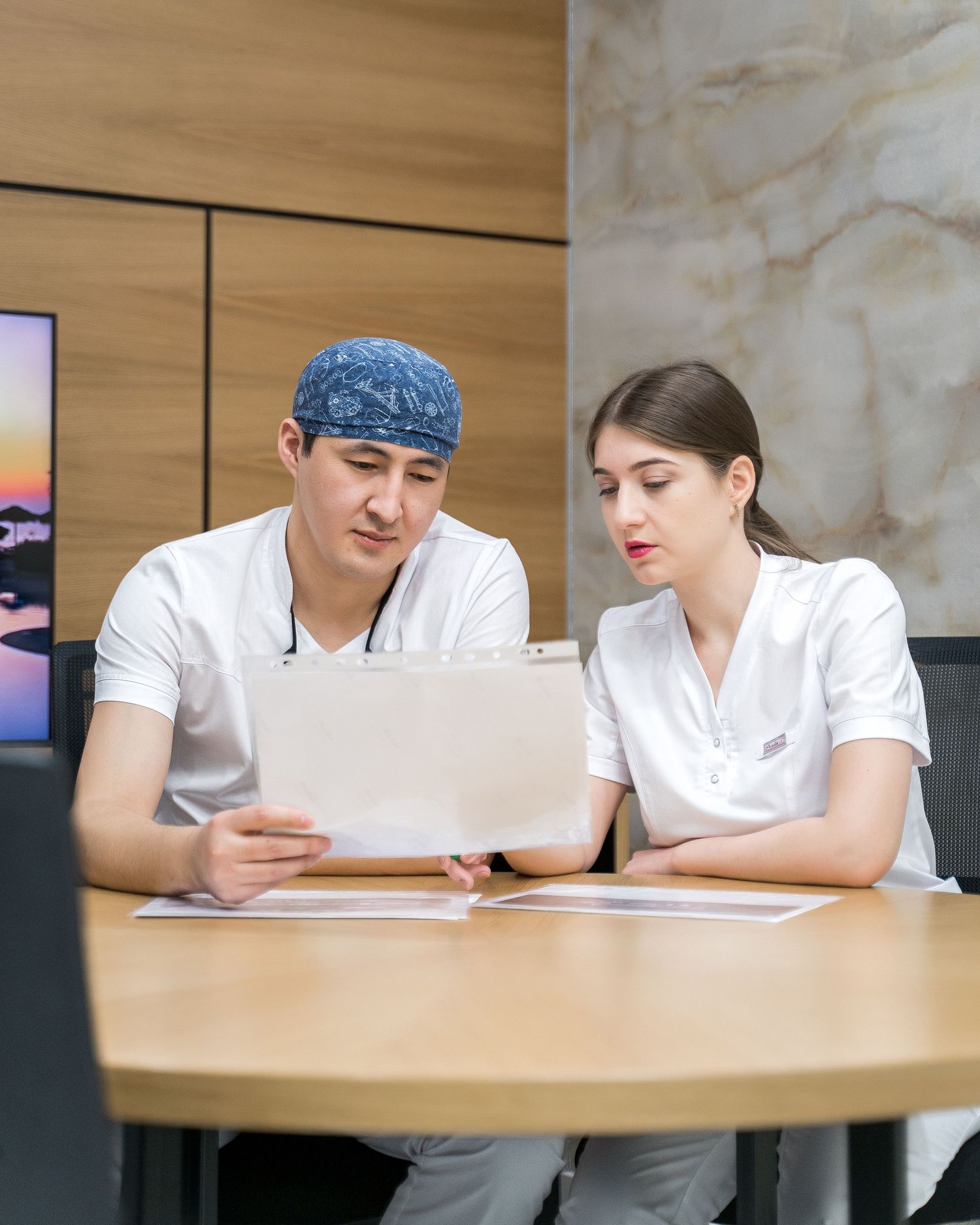 Medical professionals in white uniforms reviewing documents at conference table.