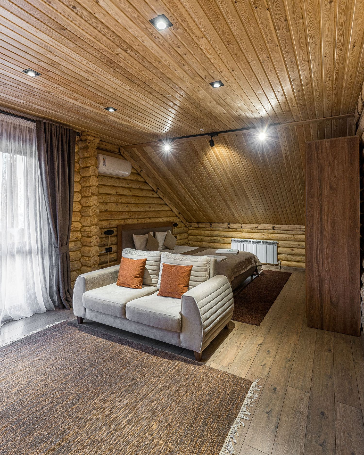 Attic living space with wooden ceiling, recessed lighting, and comfortable gray seating.