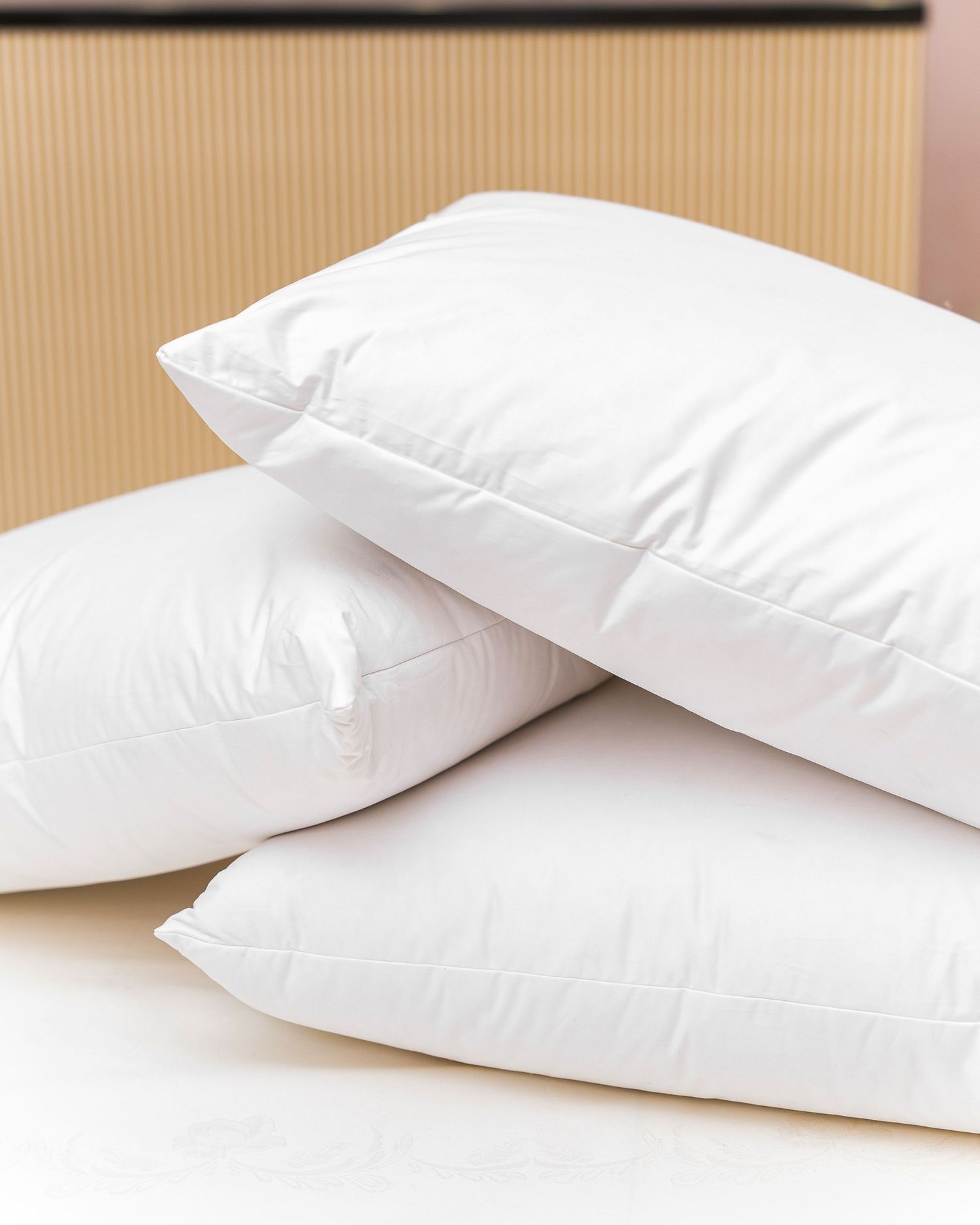 Clean white bed pillows arranged in overlapping composition on neutral background.