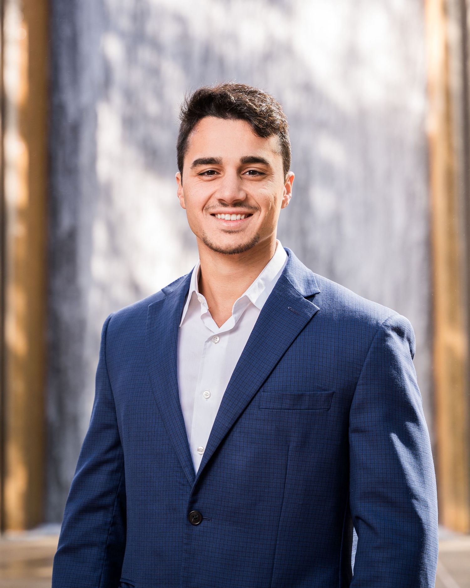 Business portrait of professional in navy suit against textured wall.