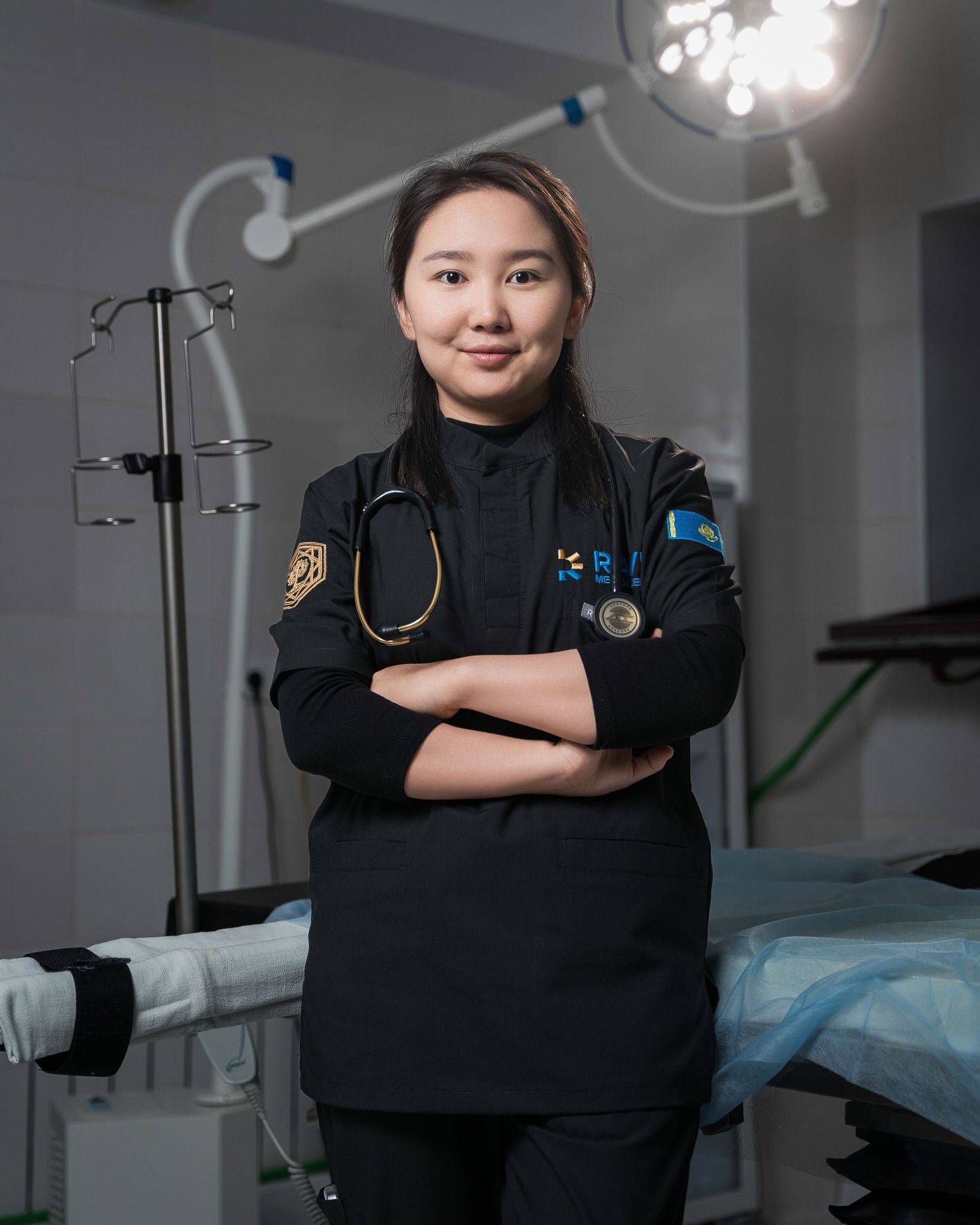 Healthcare worker in black uniform with stethoscope standing in medical facility.