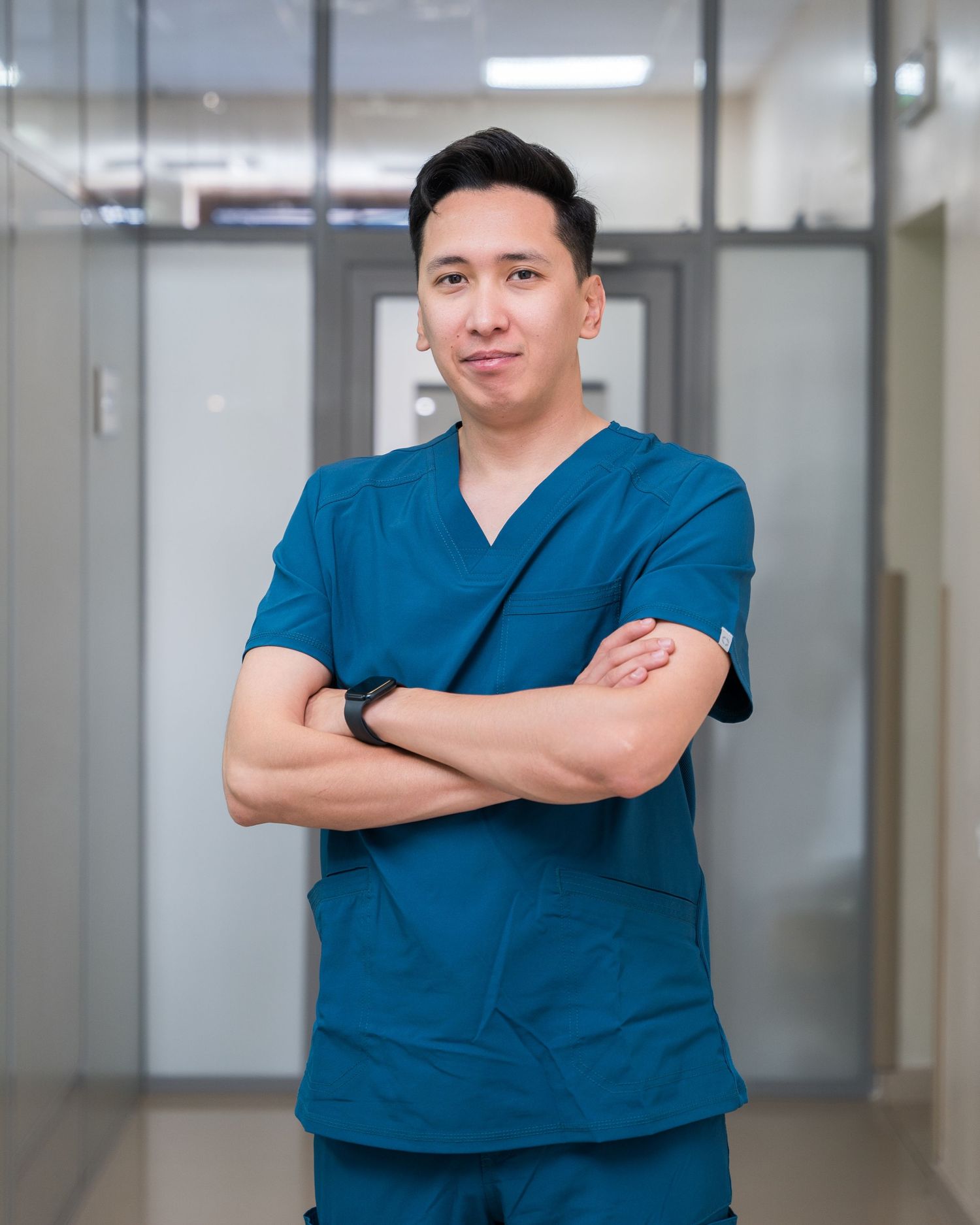 Medical professional in blue scrubs standing confidently in a hospital hallway.