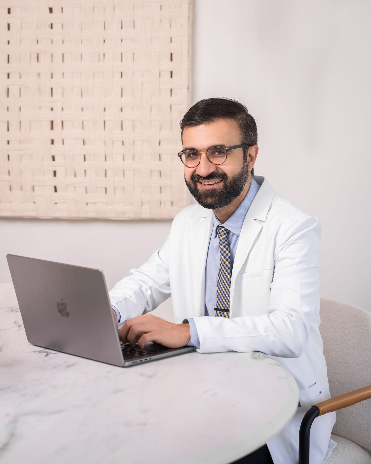 Medical professional working on laptop at desk in bright office space.