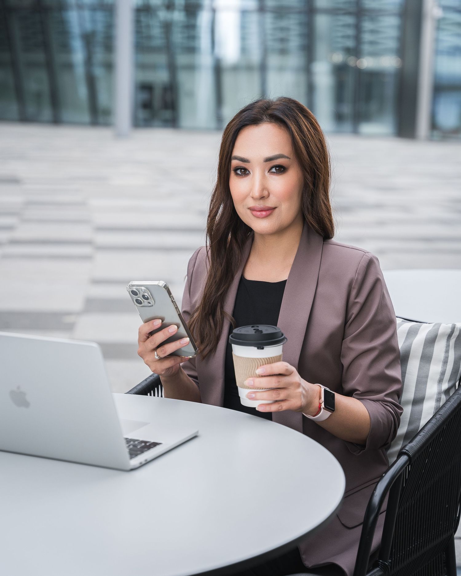 Business professional checking mobile phone while seated at modern white table.