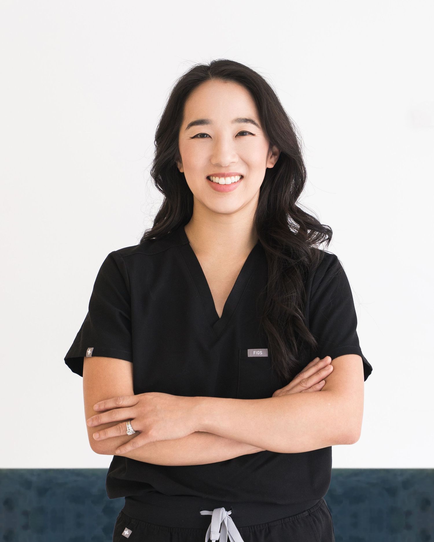Healthcare worker in black scrubs posing against white background.