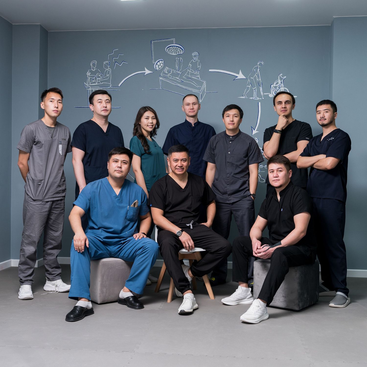 Healthcare team posing together in front of wall with medical illustrations.