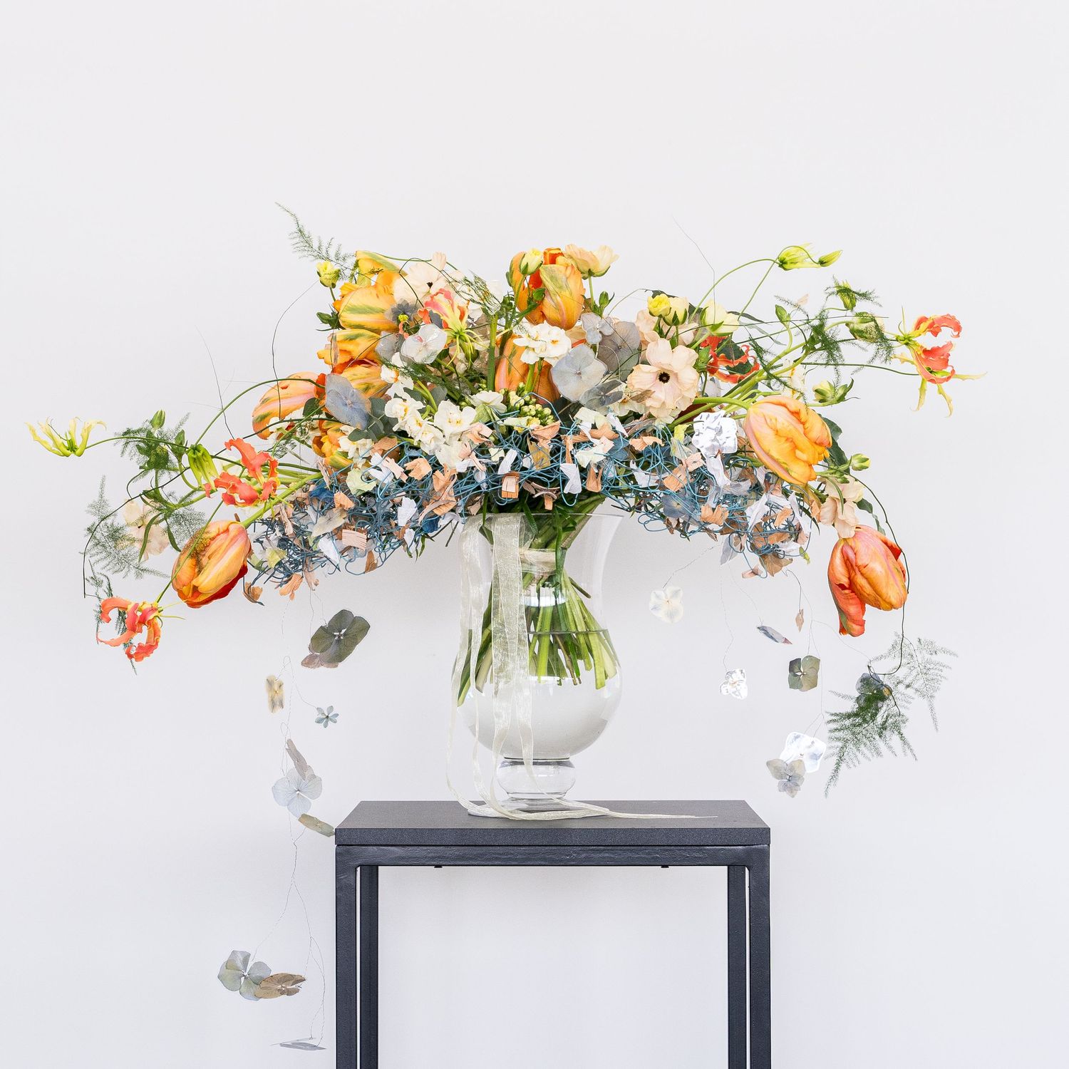 Colorful floral arrangements with orange and white blooms displayed on a white table.
