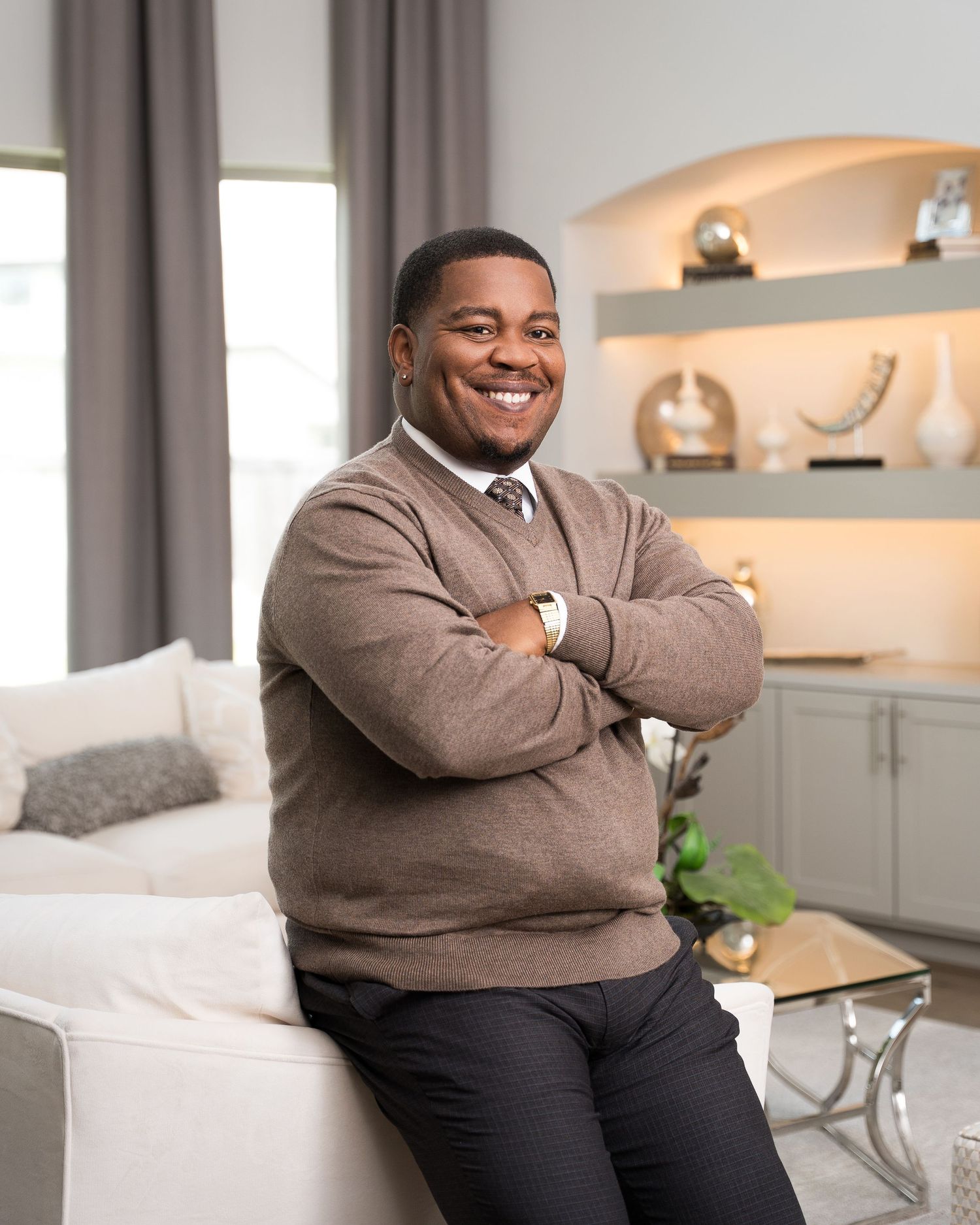 Person wearing brown sweater seated comfortably on white couch in contemporary living room.