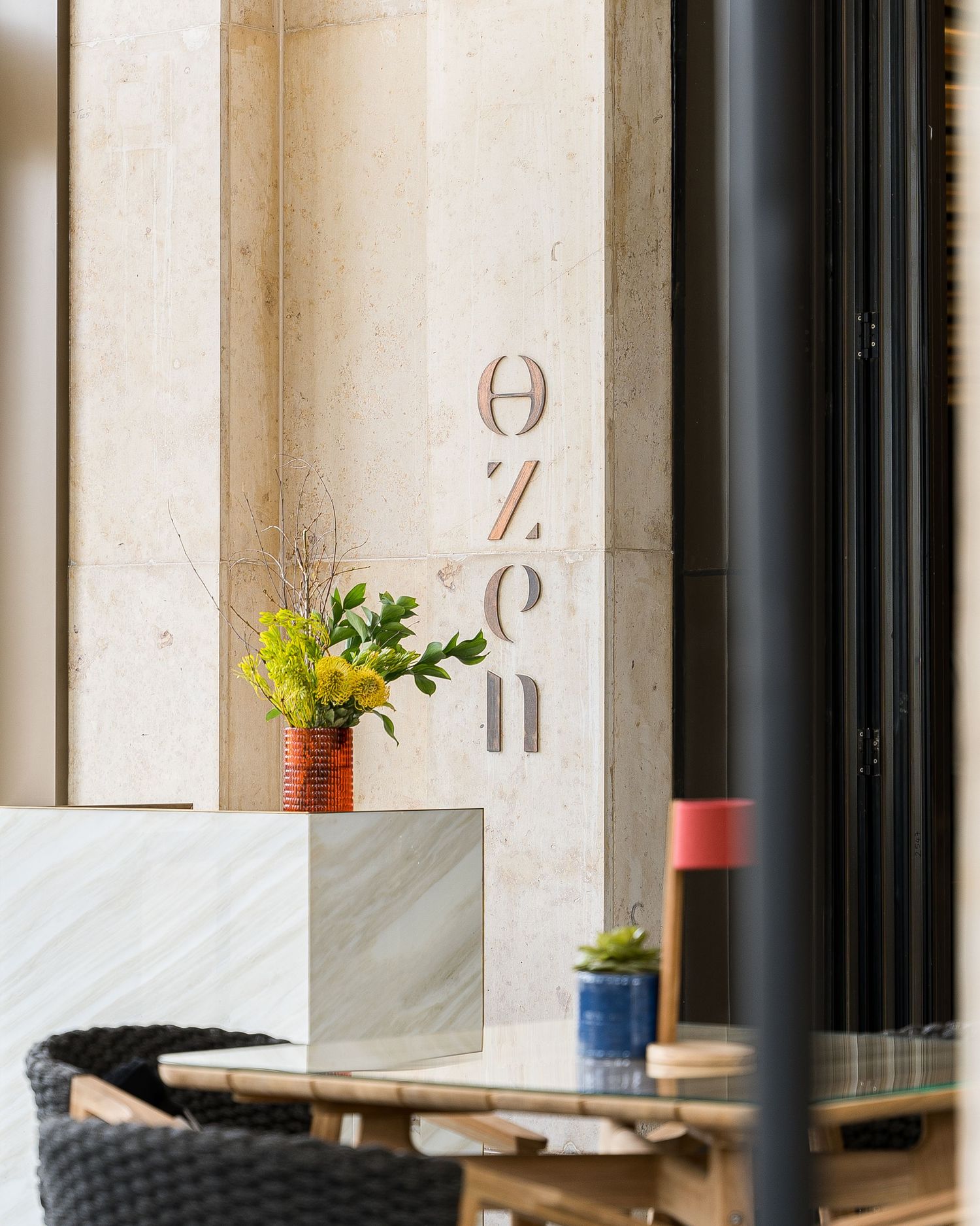 Minimalist outdoor dining area with wooden tables and decorative wall lettering.